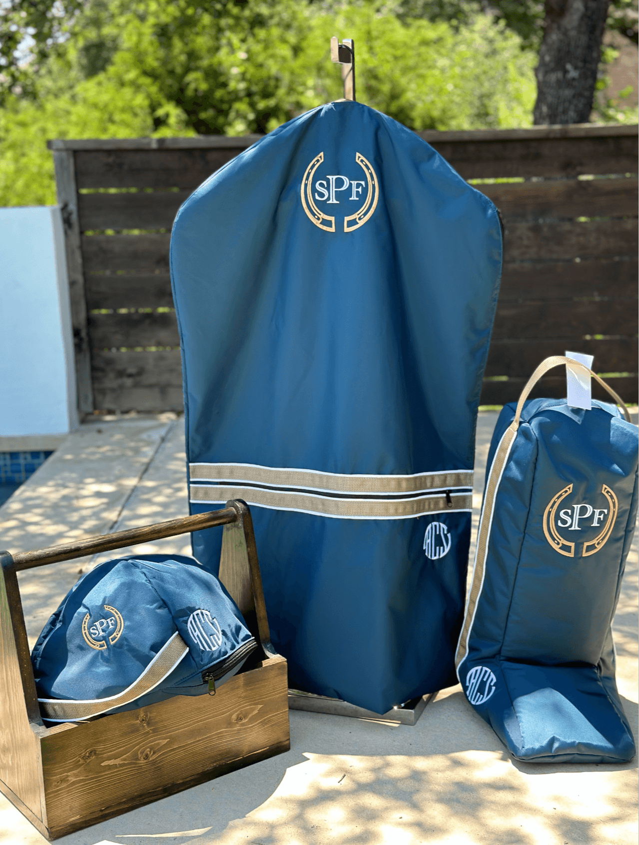 Blue protective cover with SPF logo, two matching bags, and a wooden box outdoors on a patio.