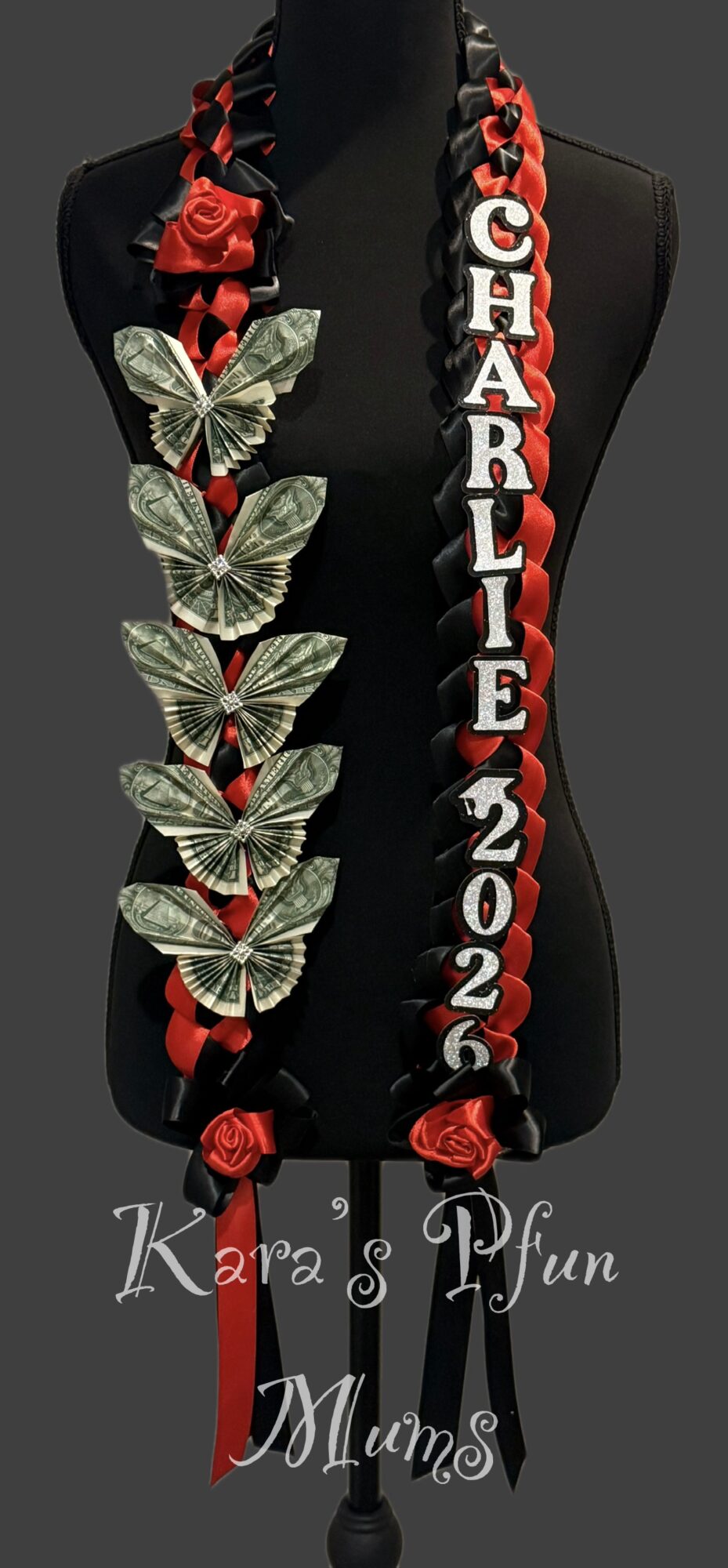 Necklace with red roses, butterflies, and a vertical name and date pendant on black background.