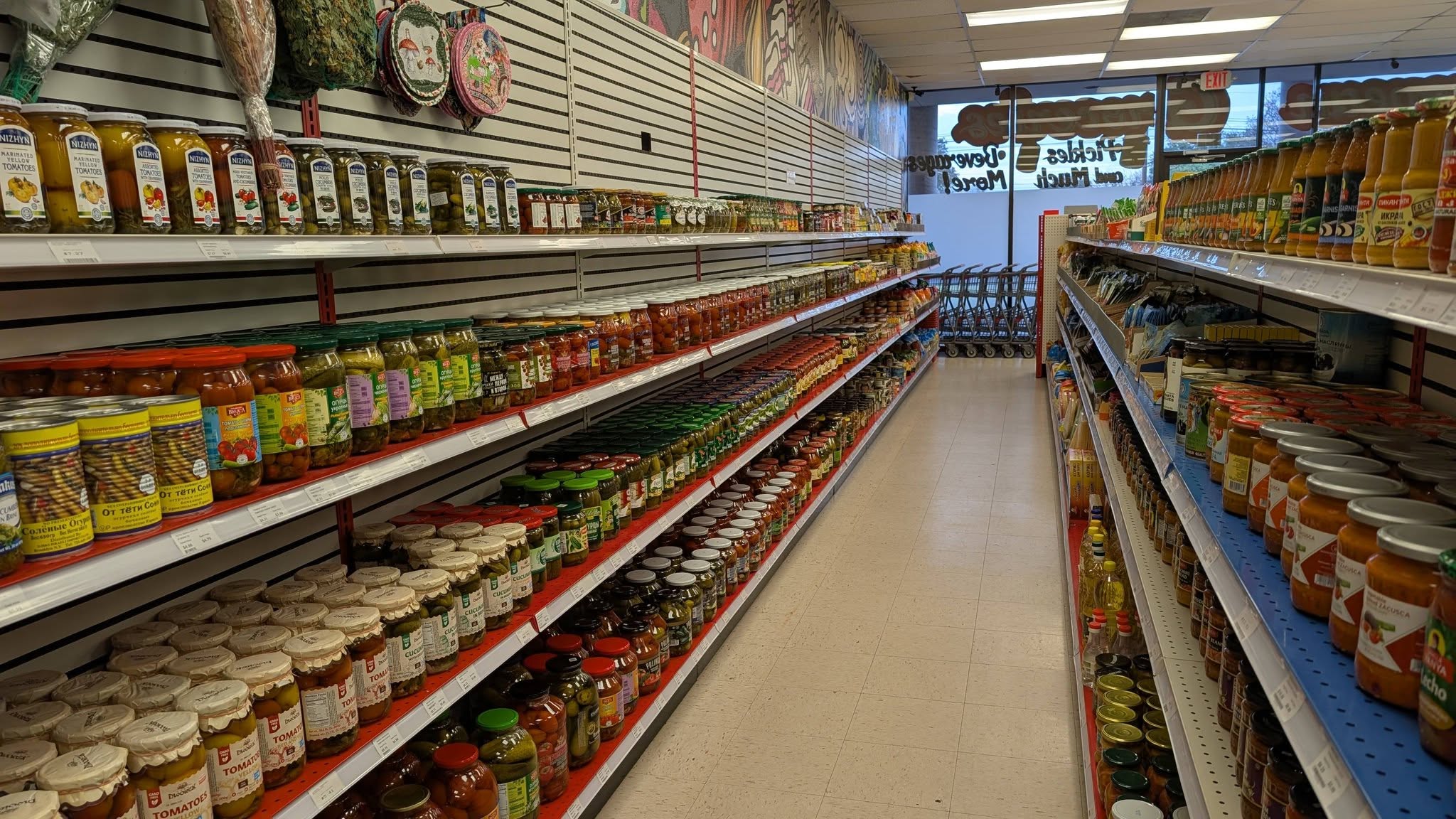 Aisle in a grocery store with shelves stocked with jars and containers on both sides, leading to the back of the store.