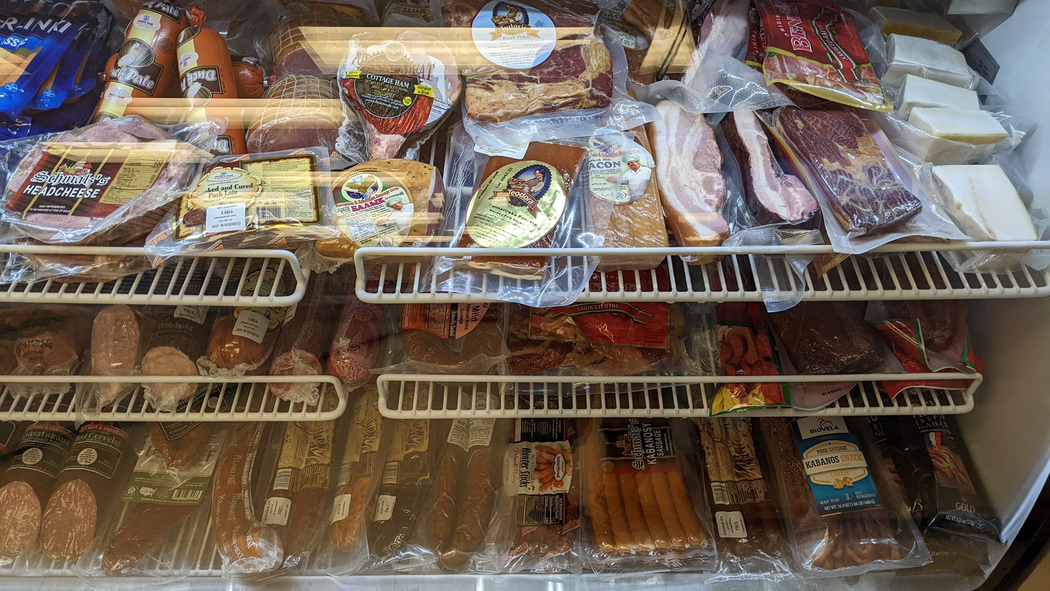 Frozen meat packages on shelves in a grocery store freezer, with various types of meat visible.