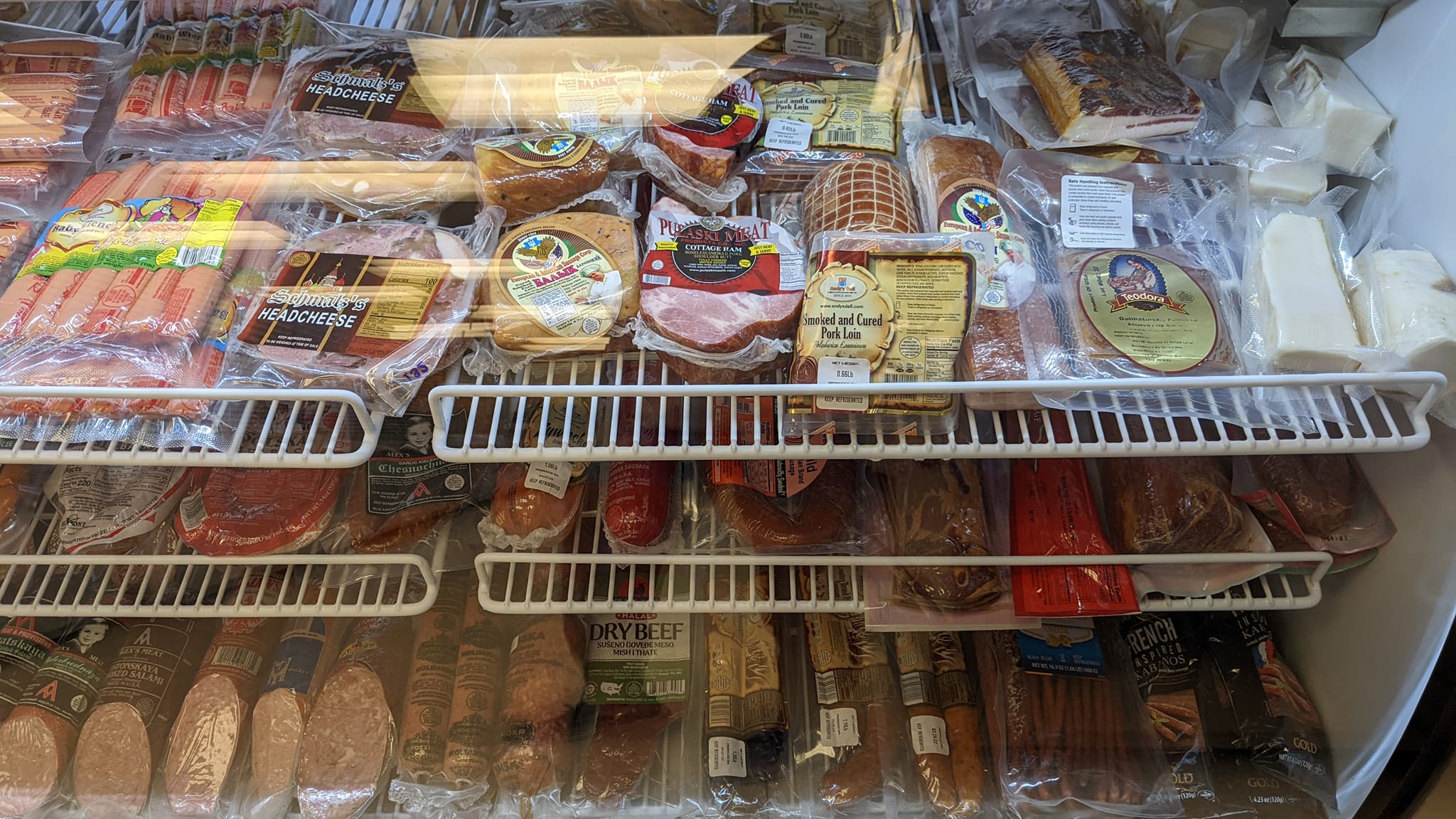 Frozen meat and packaged food items in a refrigerated display case.