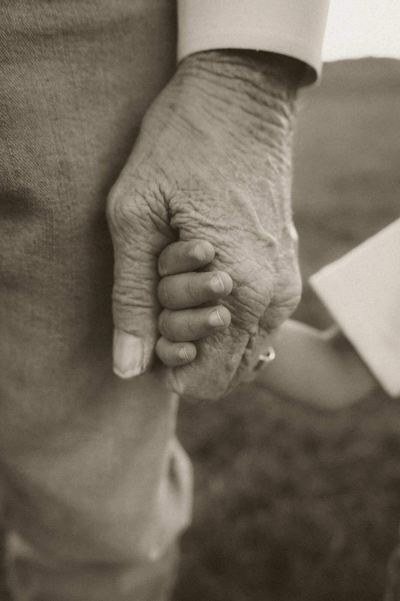 Close-up of two hands clasped together, showing wrinkles and texture, in black and white.