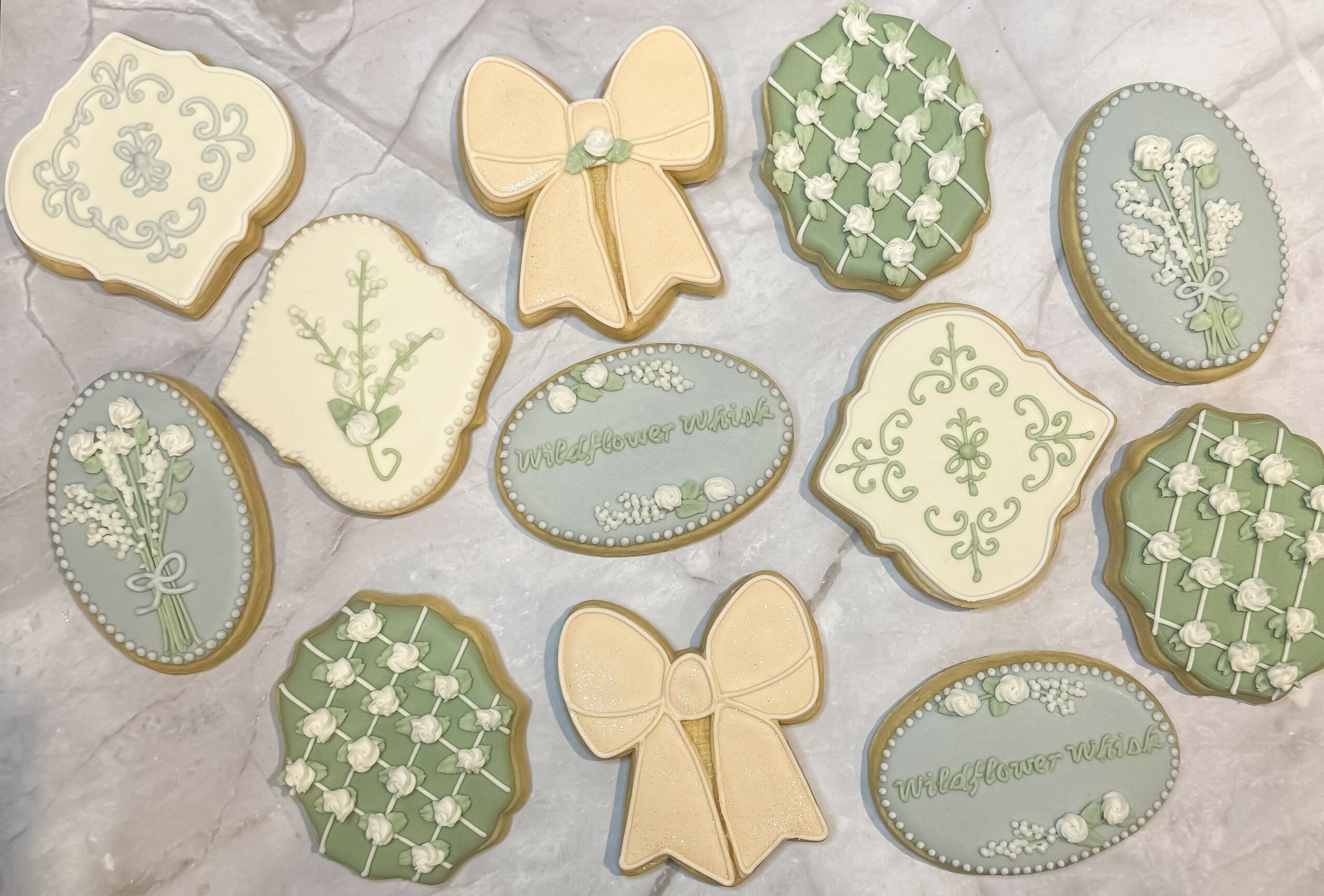 Decorative cookies with floral, bow, and geometric patterns in pastel colors on a light surface.