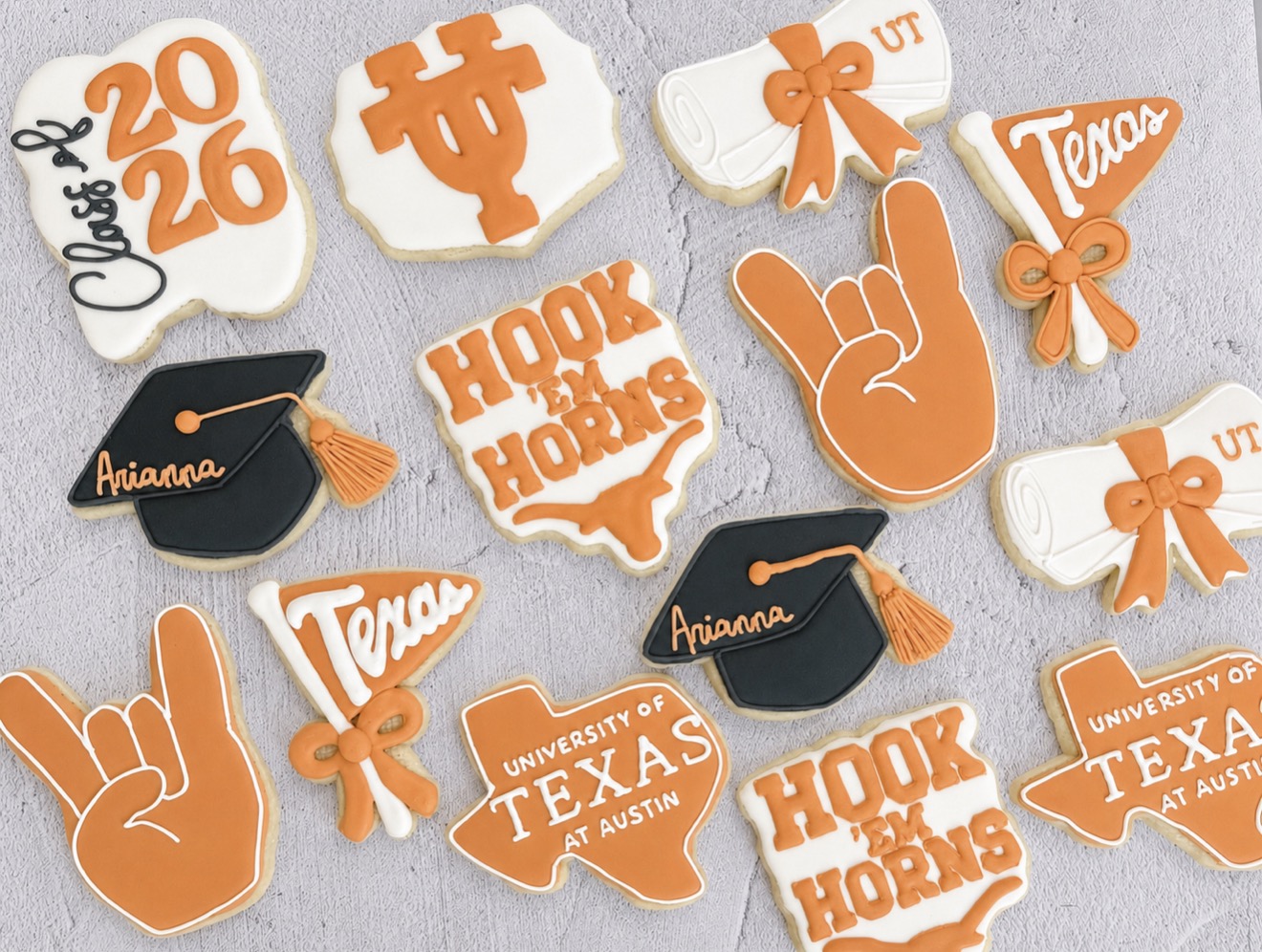 Collection of decorated cookies with Texas and university themes, including graduation caps, hand signs, and university logos.