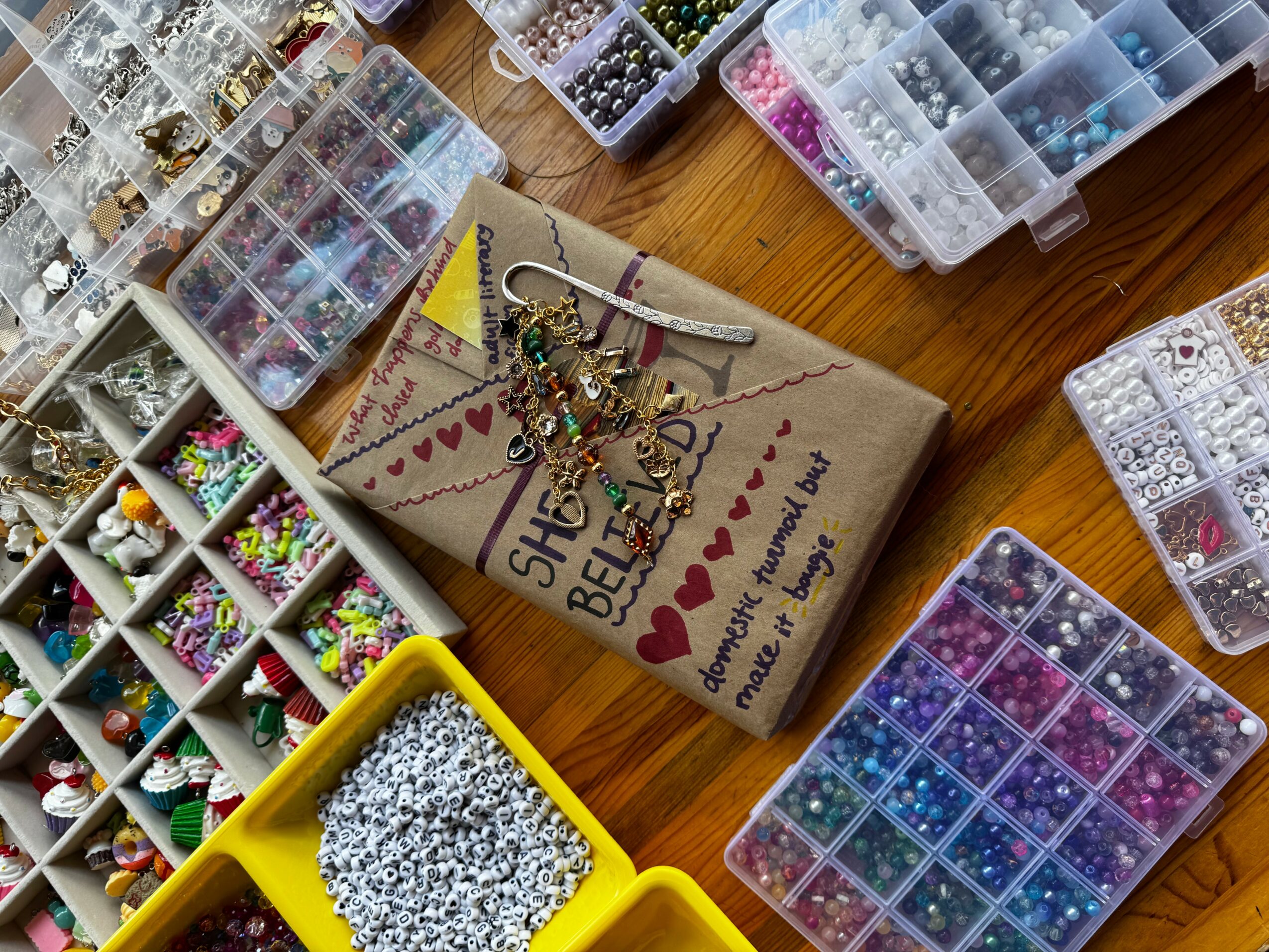 Various plastic containers filled with colorful beads and jewelry-making supplies on a wooden surface.