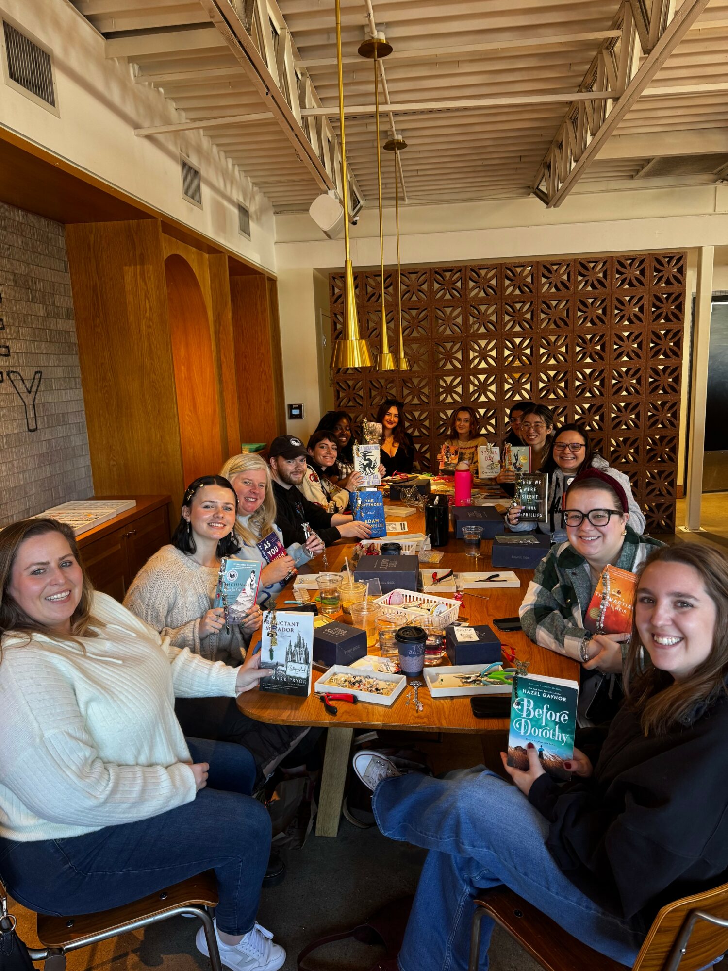 Group of people sitting around a table in a restaurant, smiling and enjoying food and drinks.
