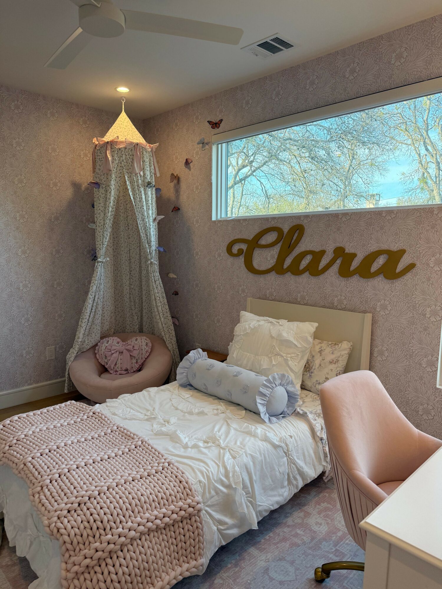 Bedroom with bed, window, and wall decoration, viewed from the side, with natural light coming in.