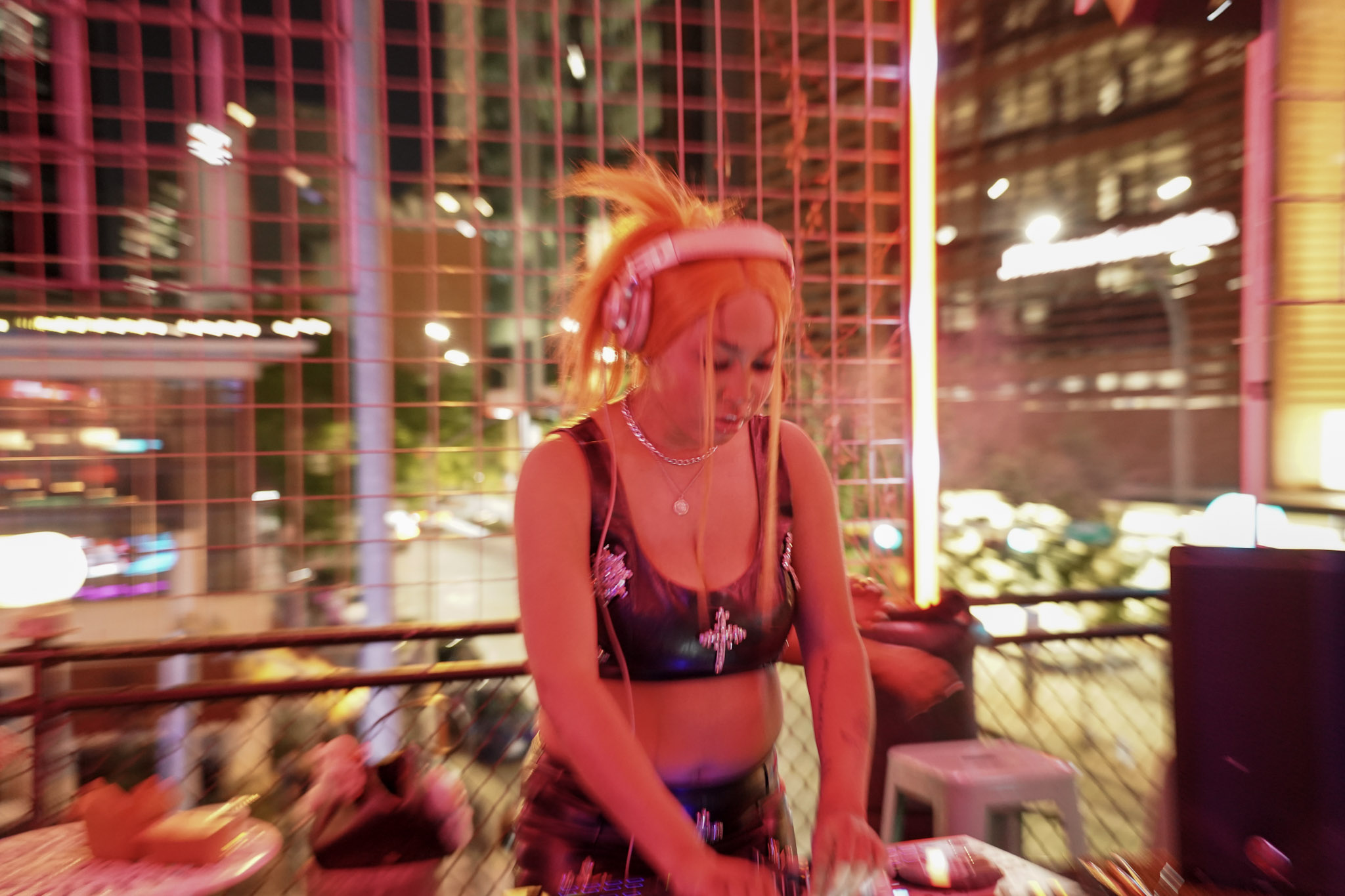 Woman with blonde hair in a ponytail, wearing a black top, standing inside a colorful, illuminated structure at night.