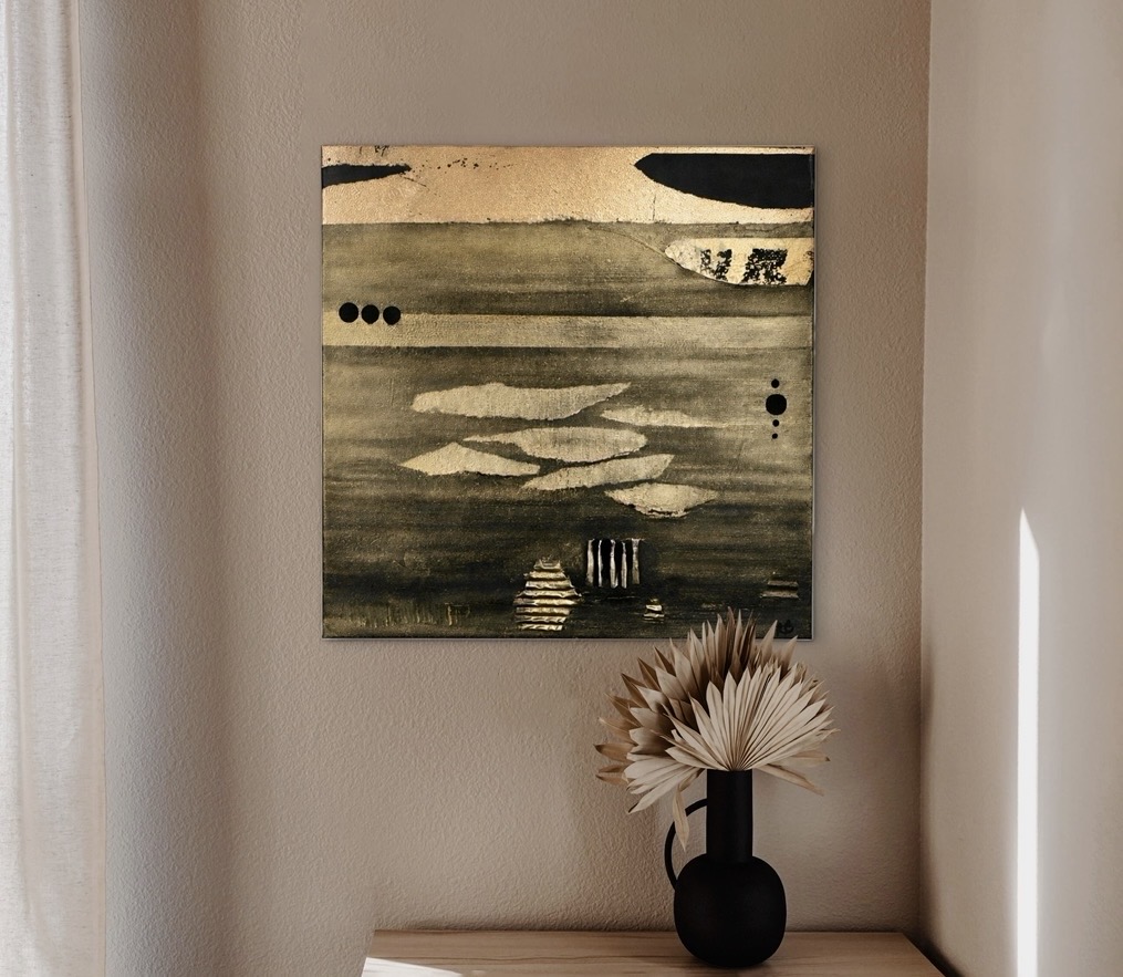 Abstract landscape painting with water and sky, above a black vase with a large white flower, on a wooden surface.