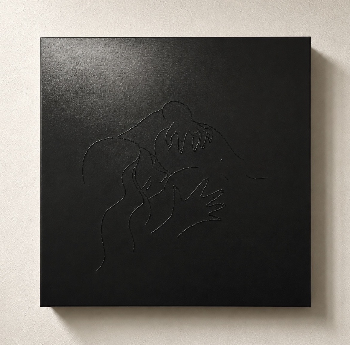 Black square artwork with embossed outline of a person's face and hand, minimalistic design.