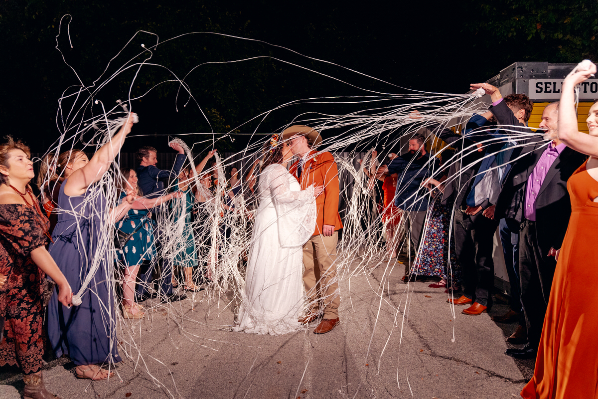 People at a celebration throw streamers over a couple dancing in the center at night.