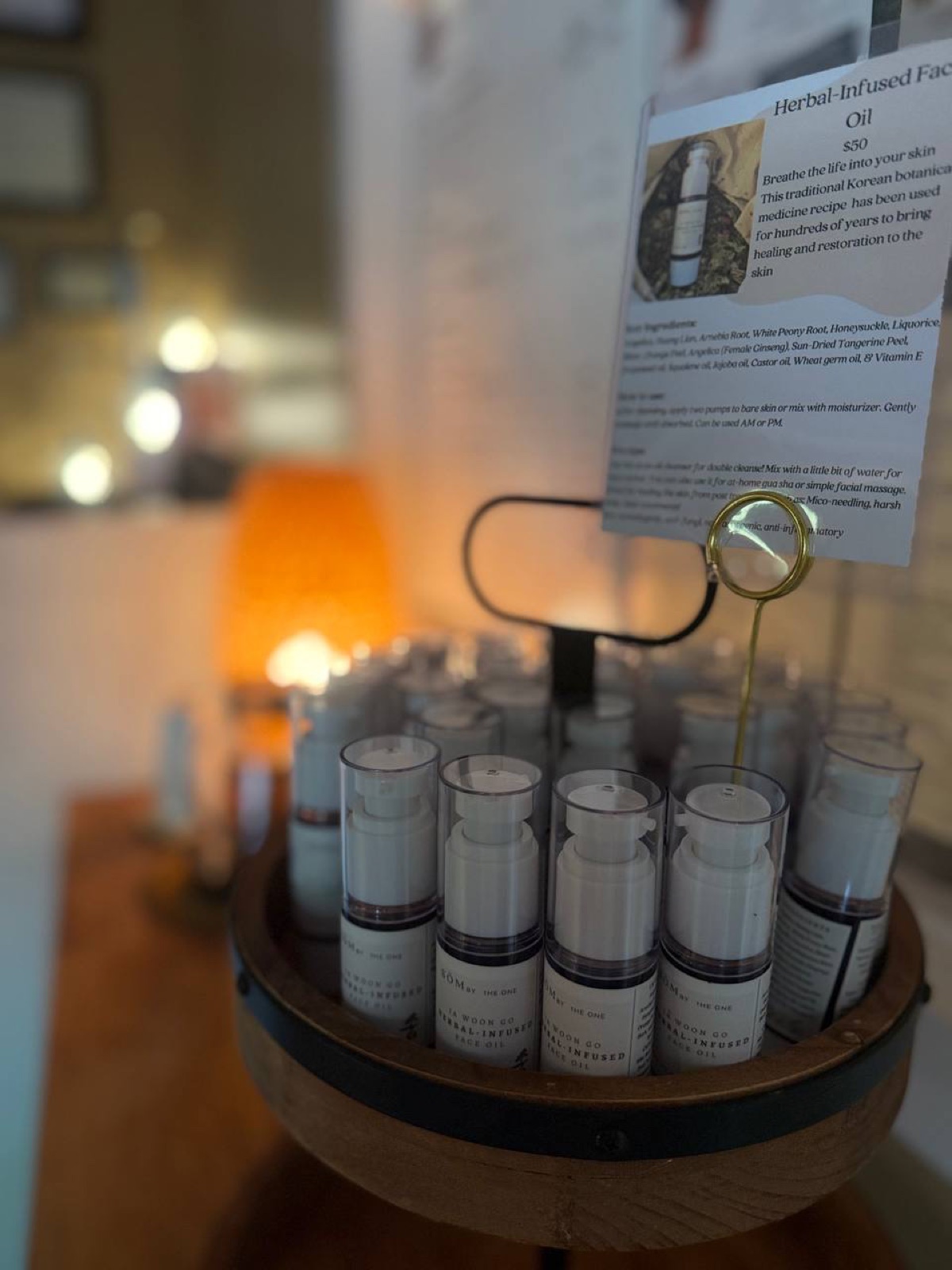 Display of small bottles with labels, a sign with text and an image, in a wooden stand, indoors.