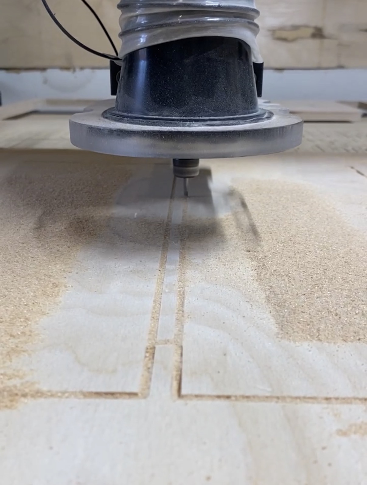 A close-up of a machine cutting a tile, with dust and a straight line guide visible, viewed from below.