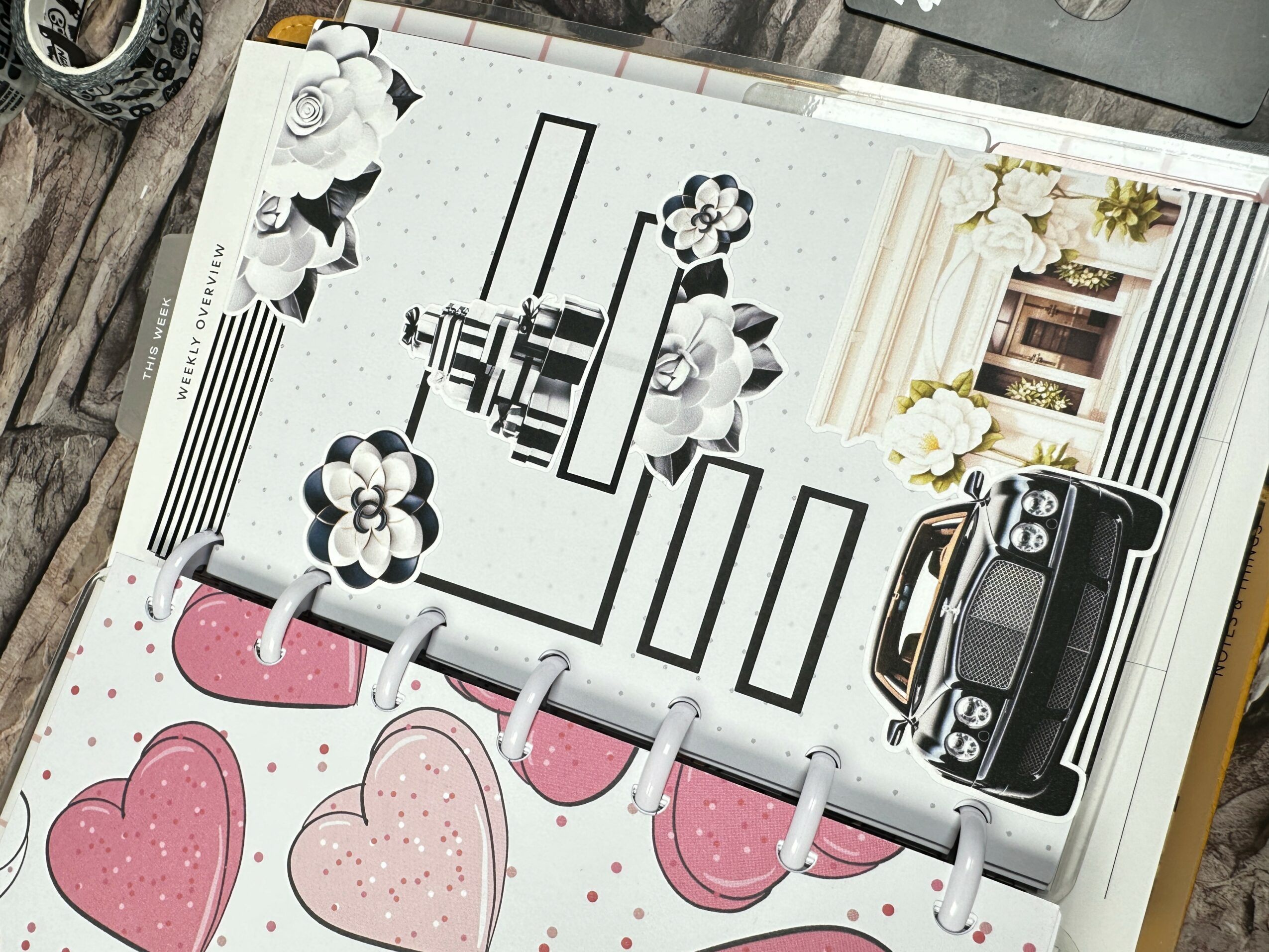 Open book with black and white illustrations, pink hearts, and a black camera on a white surface.