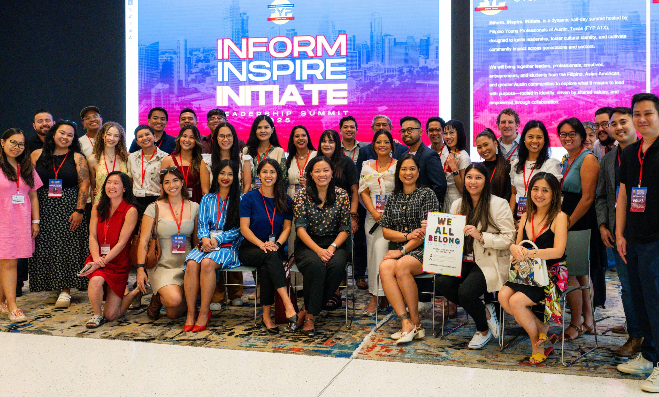 Group of people posing in front of a large screen with colorful text and cityscape background, some holding a sign.