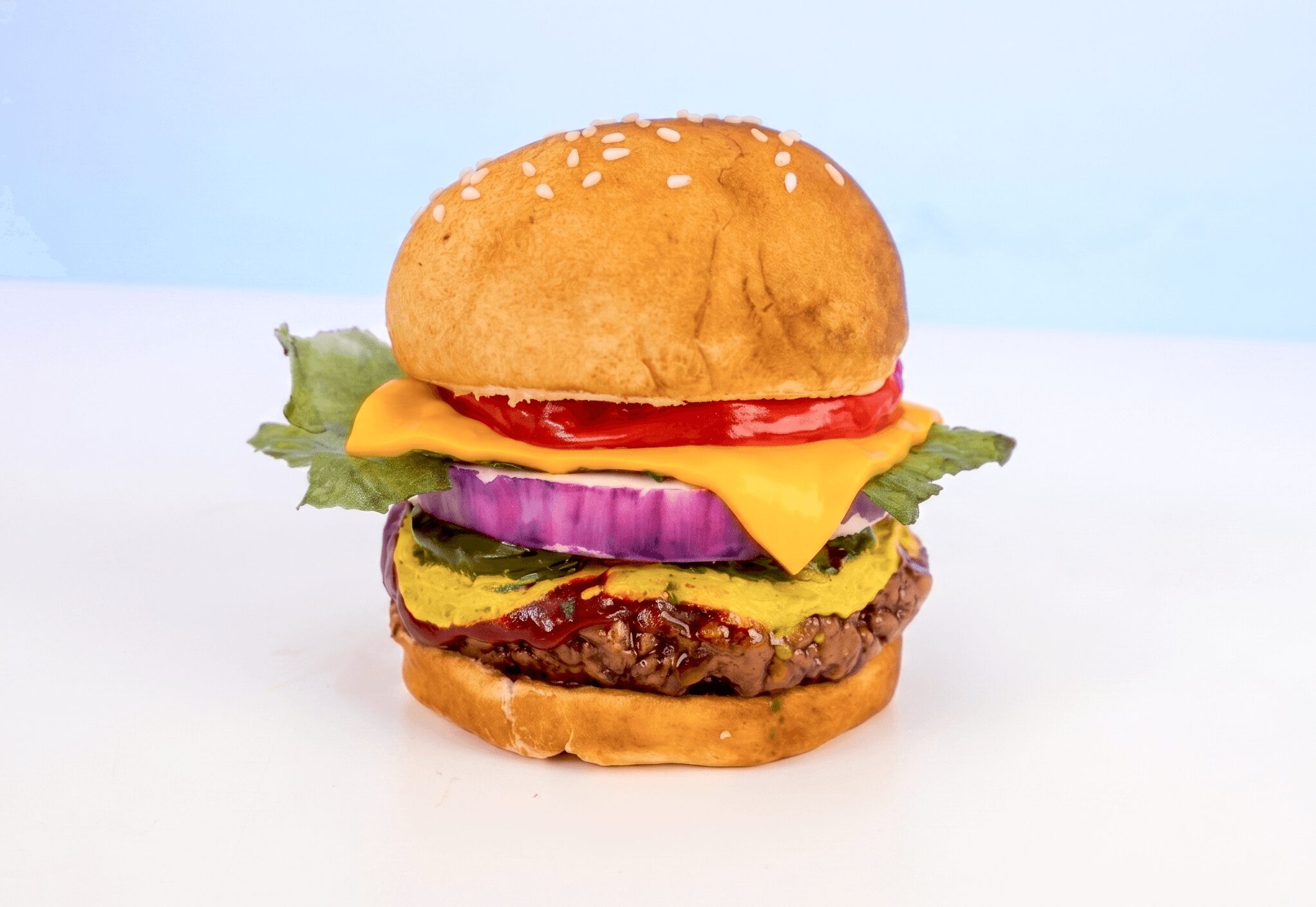 Hamburger with lettuce, tomato, cheese, onion, and a beef patty in a bun, on a white background.
