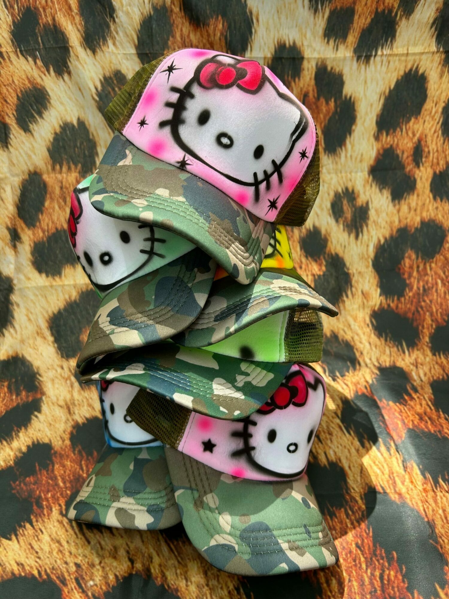 Colorful fabric with Hello Kitty faces and camouflage pattern, placed on a leopard print background.
