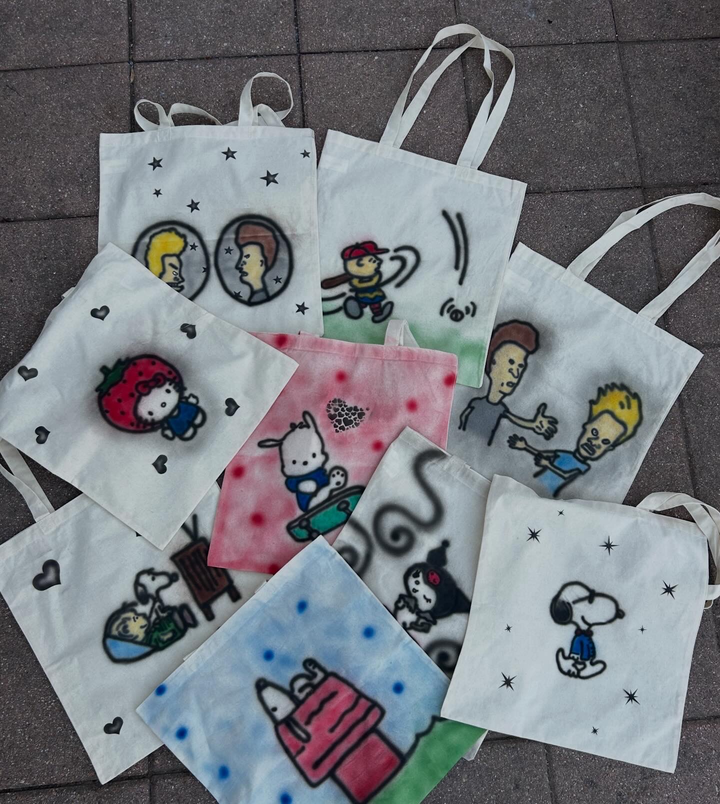 Multiple tote bags and cloths with cartoon characters and designs, some with stars and polka dots, on a tiled surface.