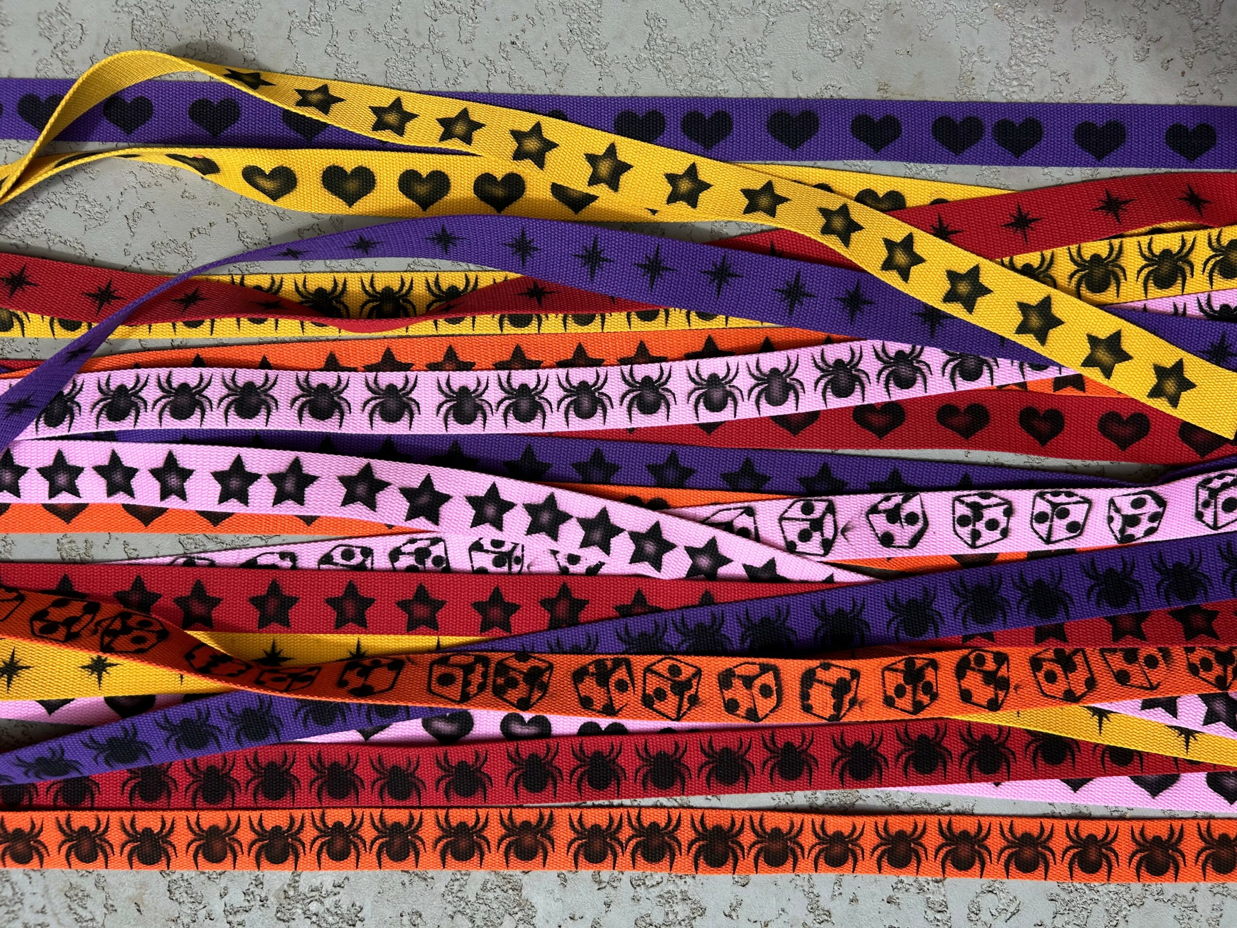 Multiple colorful ribbons with Halloween-themed patterns, including spiders, skulls, bats, and stars, arranged horizontally.