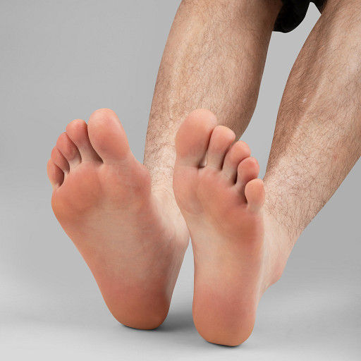 Close-up of bare feet with toes pointing upward, legs visible, against a plain background.
