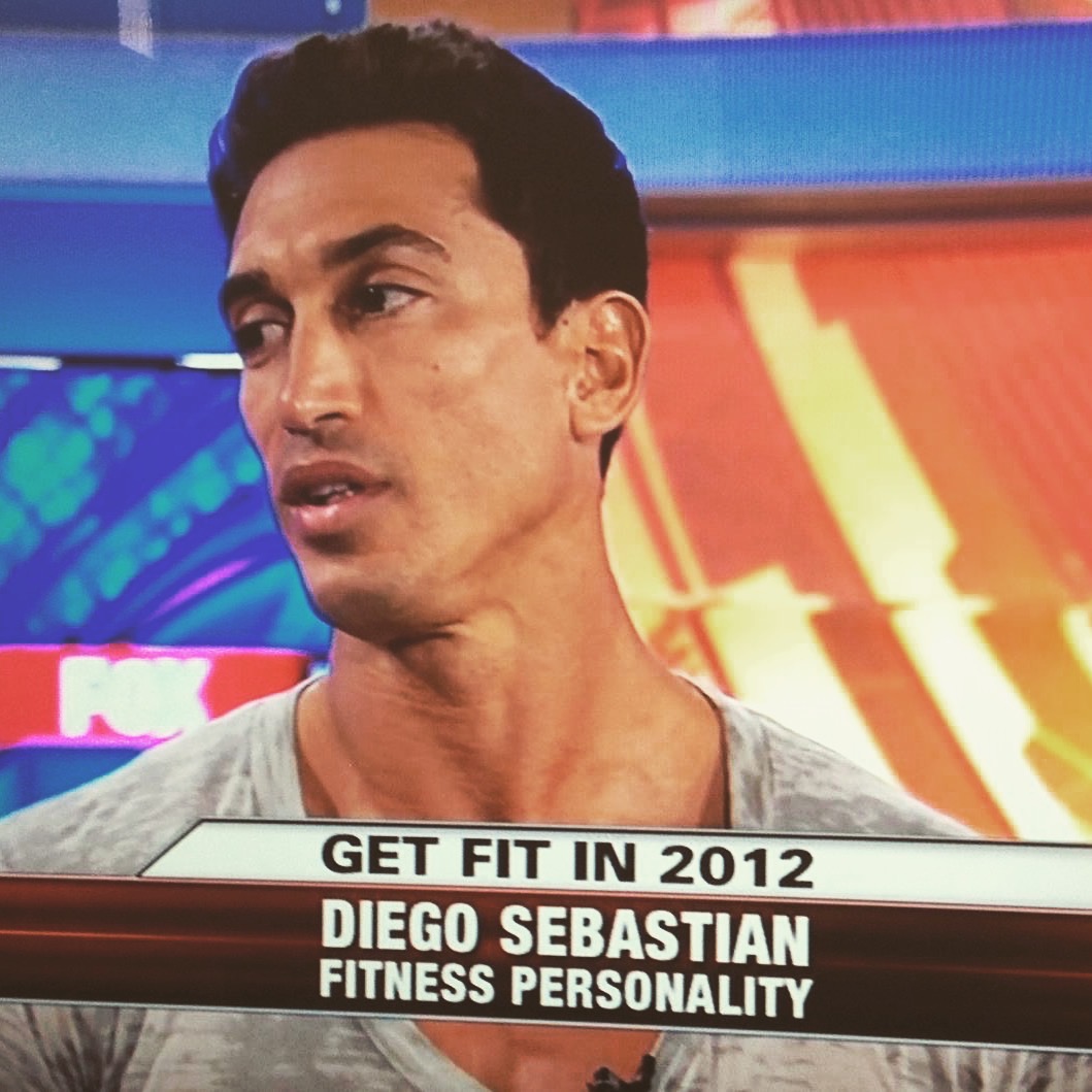 Man with dark hair and gray shirt on a TV set, text about fitness personality, 2012.