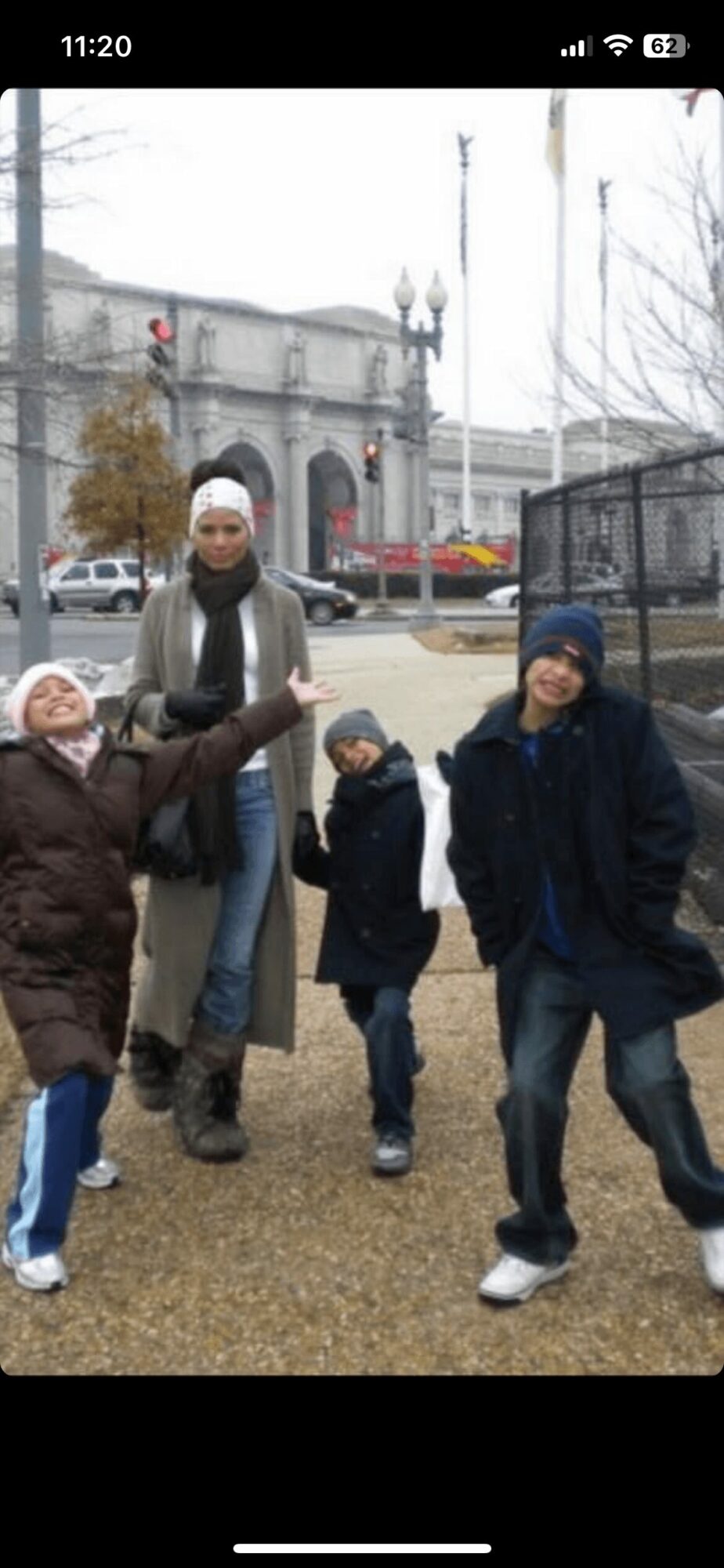 Four children and an adult standing outdoors in front of a historic building, some children are smiling and posing.