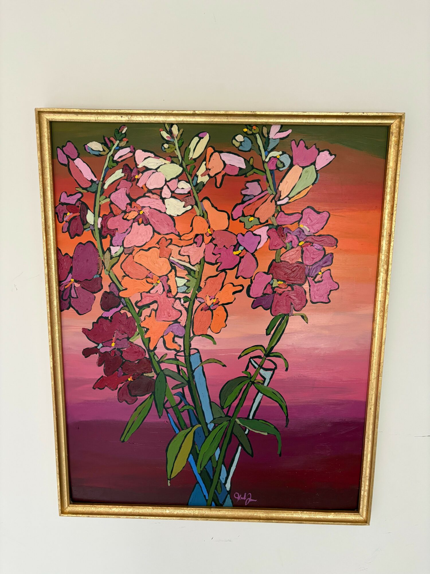 Framed painting of colorful flowers against a pink and purple background, tilted sideways.