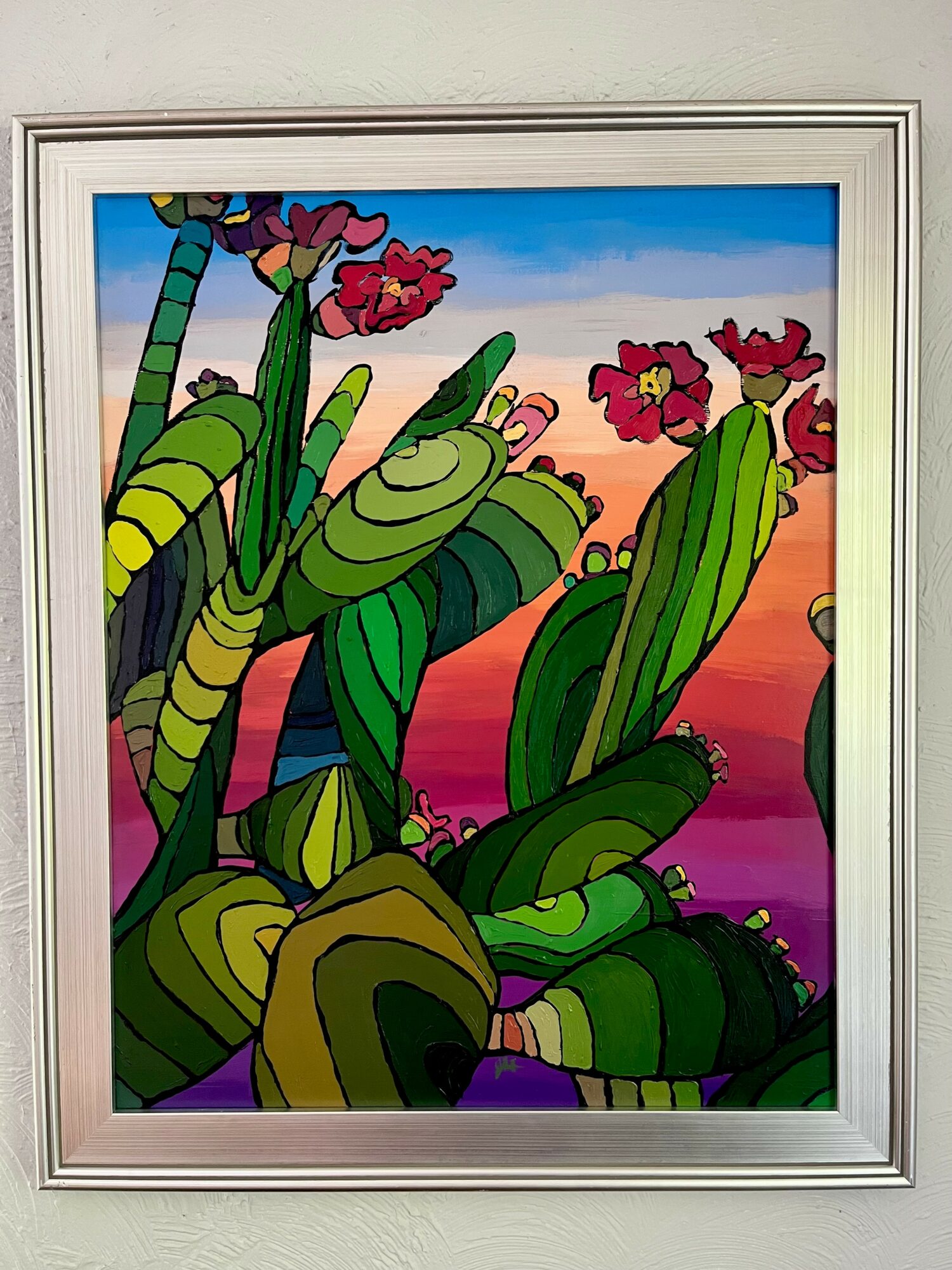 Colorful cactus plants with pink flowers against a vibrant sunset sky, framed in a silver border.