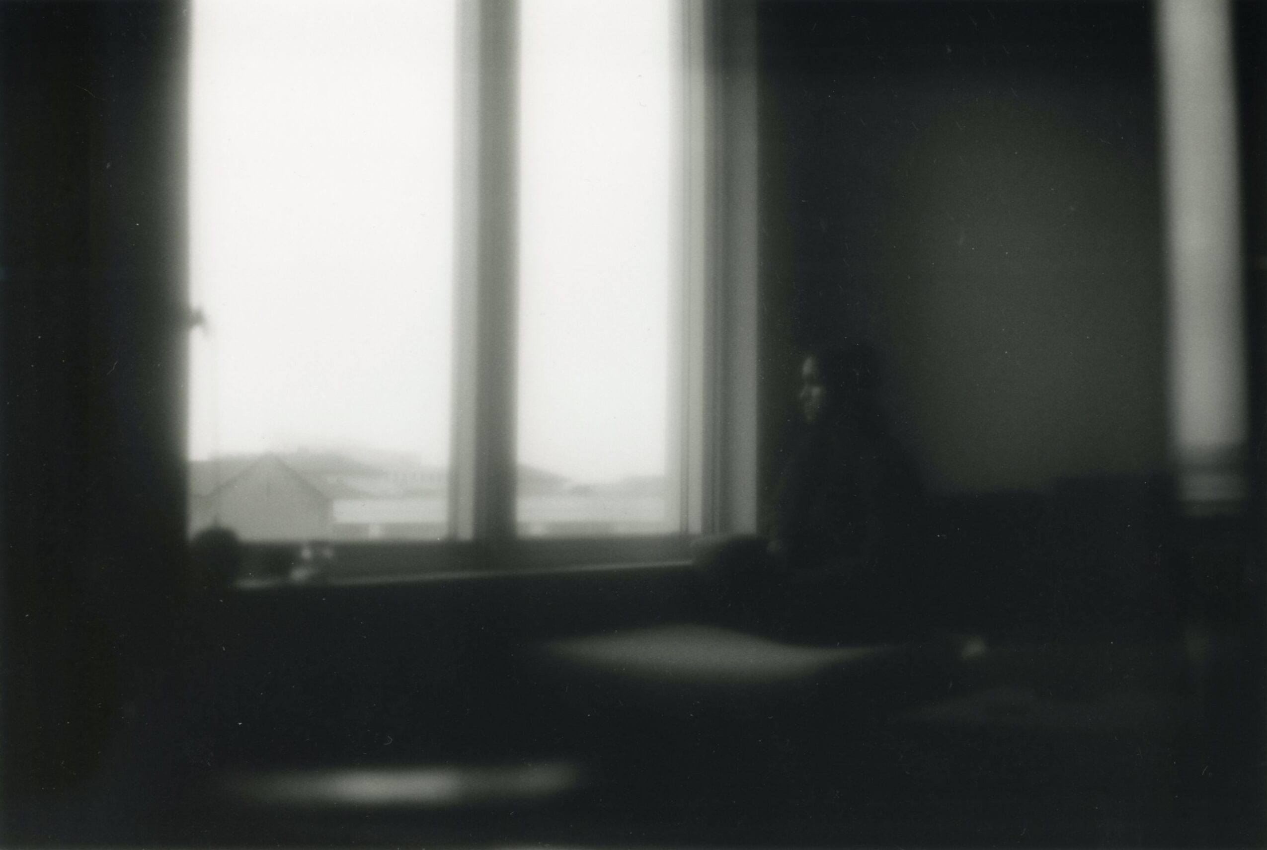 View through a window with bright light outside, dark interior, and a small object on the windowsill.
