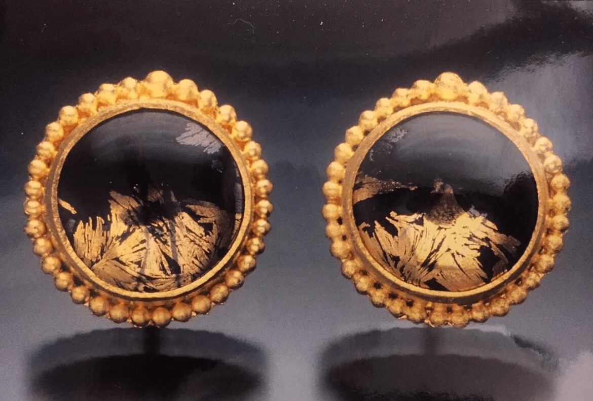 Two round objects with decorative beaded borders and dark reflective centers, placed on a dark surface.