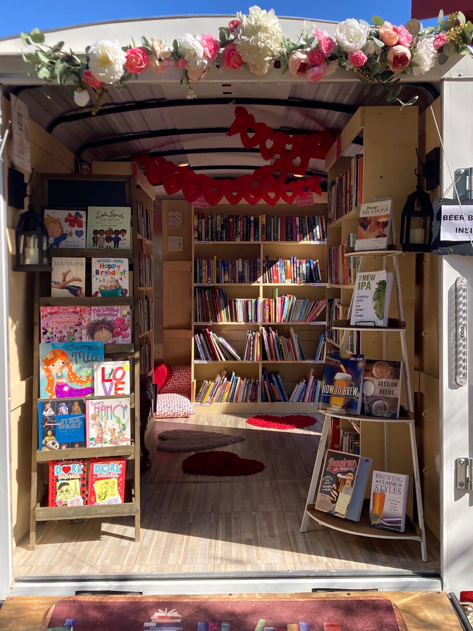 Open bookstore entrance decorated with flowers and red paper chains, revealing shelves filled with books inside.