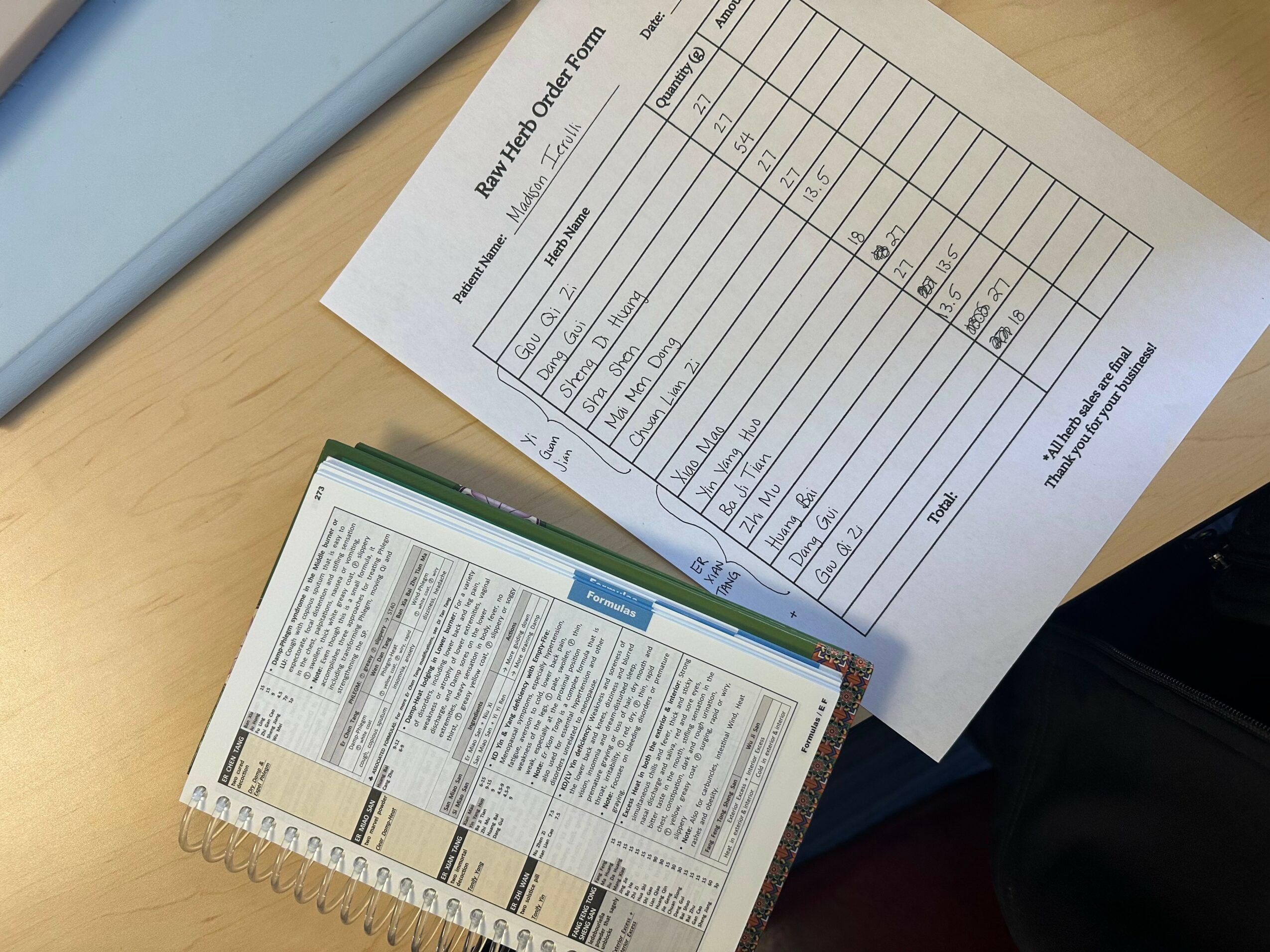 A printed document with a table and a book with text on a wooden surface, partially visible.