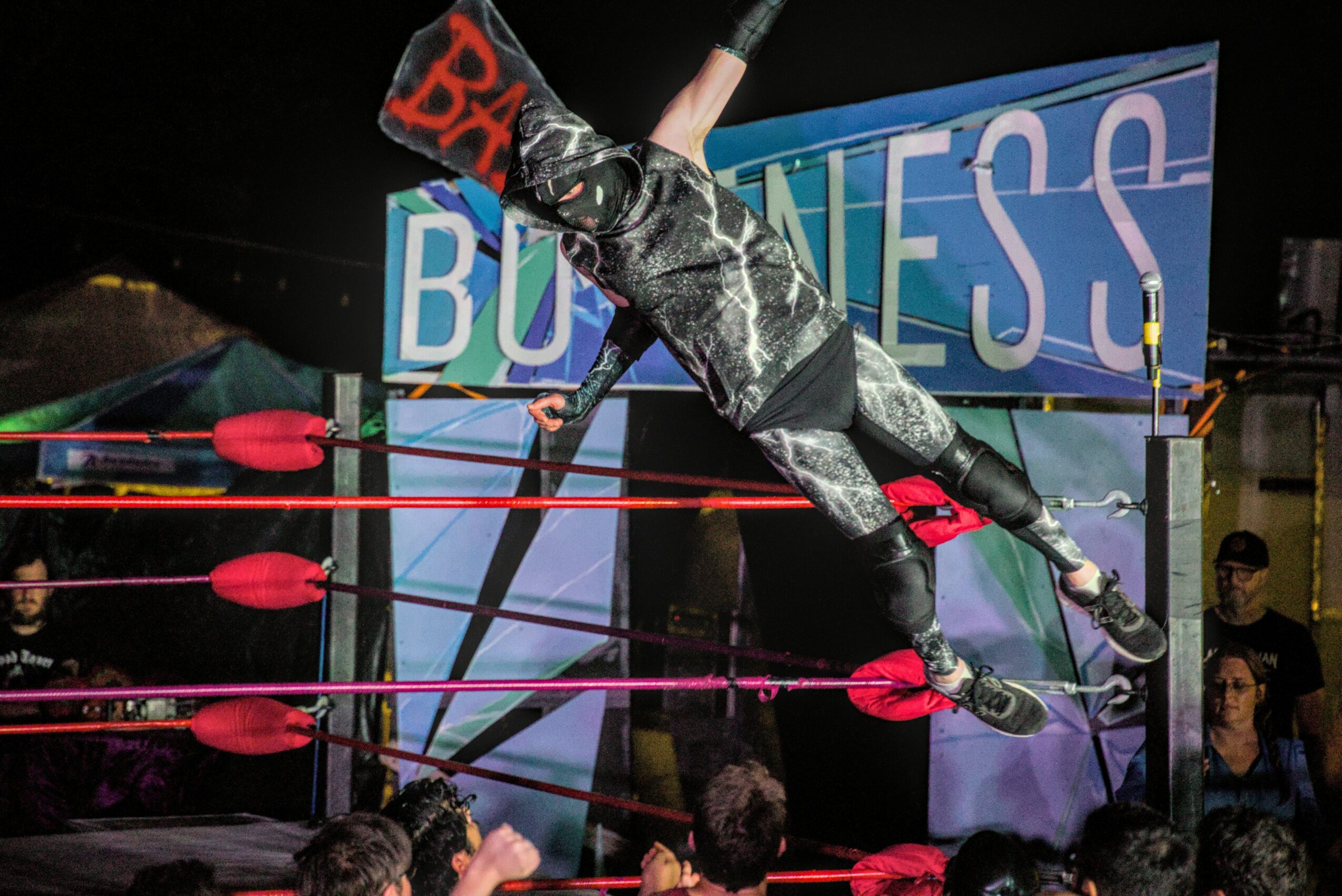 Wrestler performing a high-flying move in a wrestling ring with a