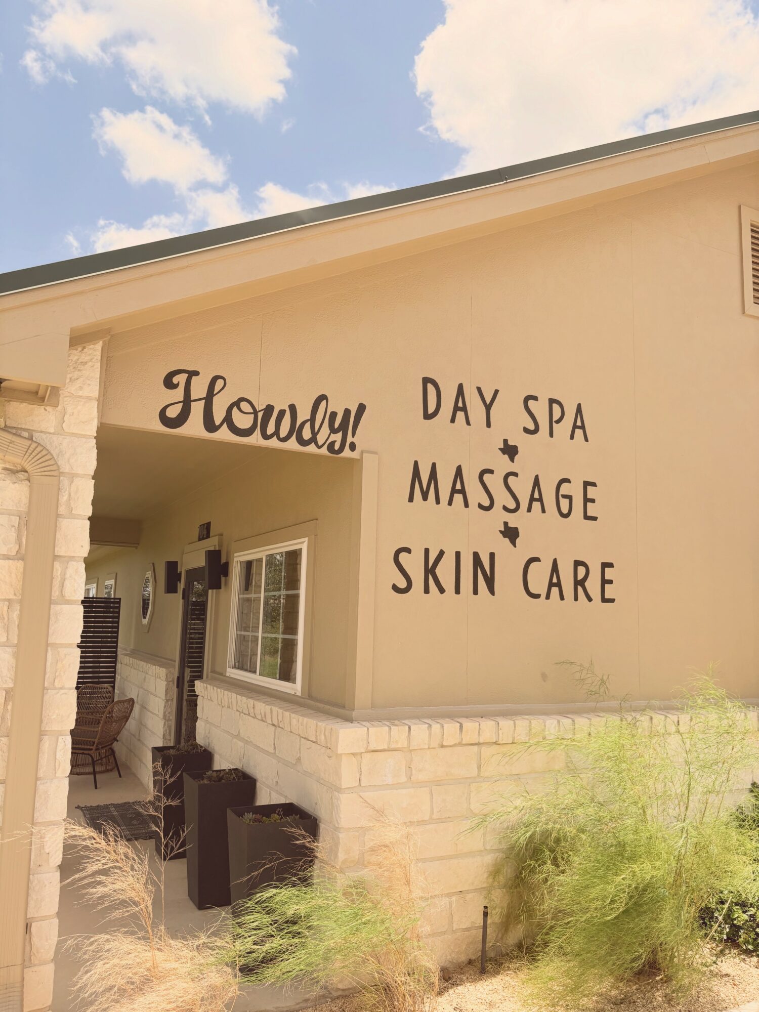 Exterior of a building with signs for a day spa, massage, and skin care, under a partly cloudy sky.