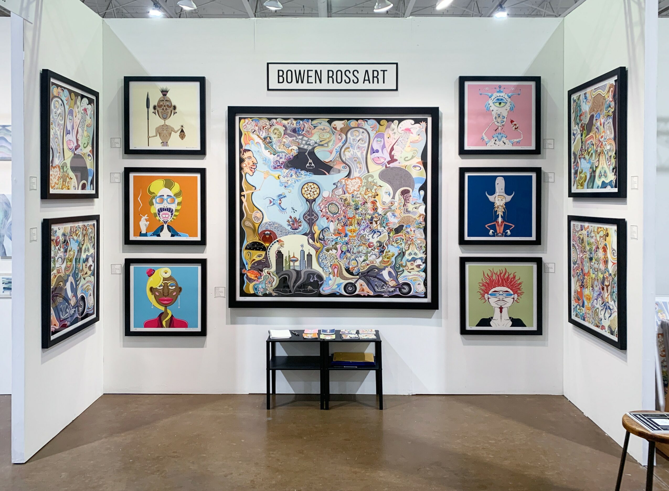 Art gallery with colorful paintings on white walls, a bench in the center, and a sign reading 'BOWEN ROSS ART'.