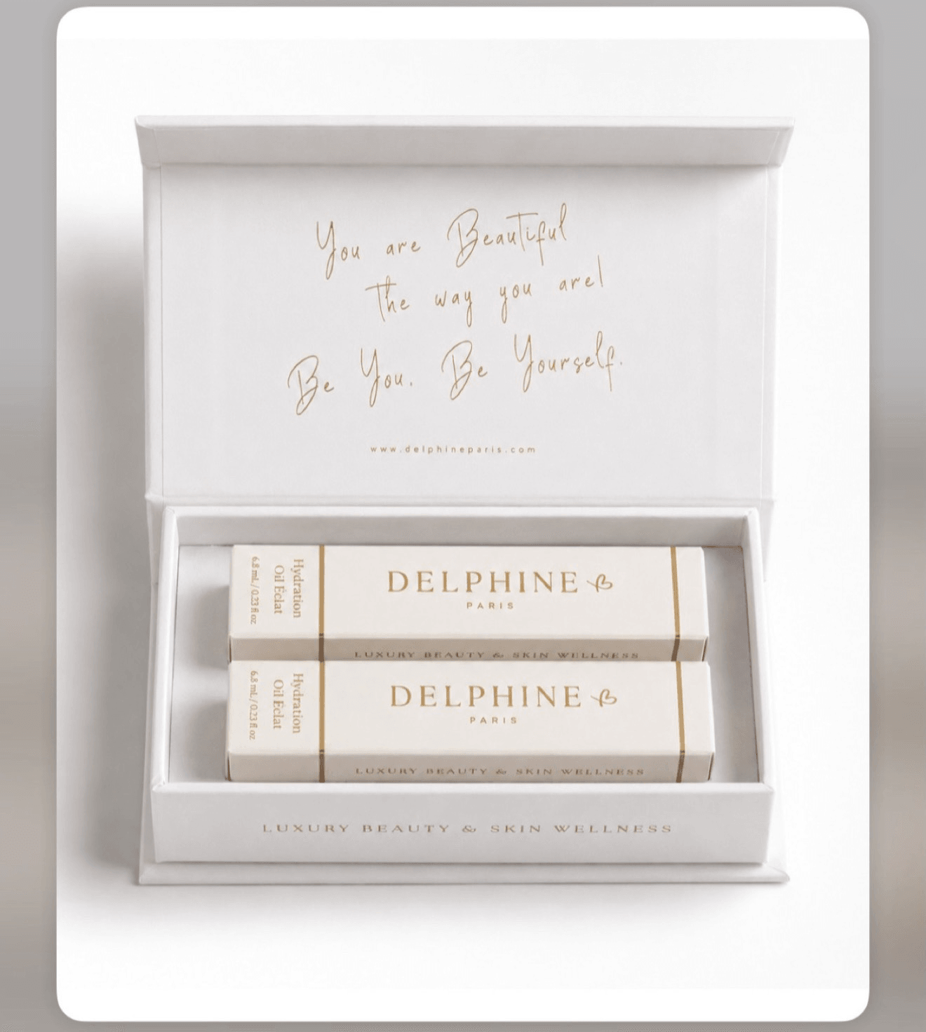 Open white box with gold text inside lid, containing two white boxes labeled Delphine, on a white surface.