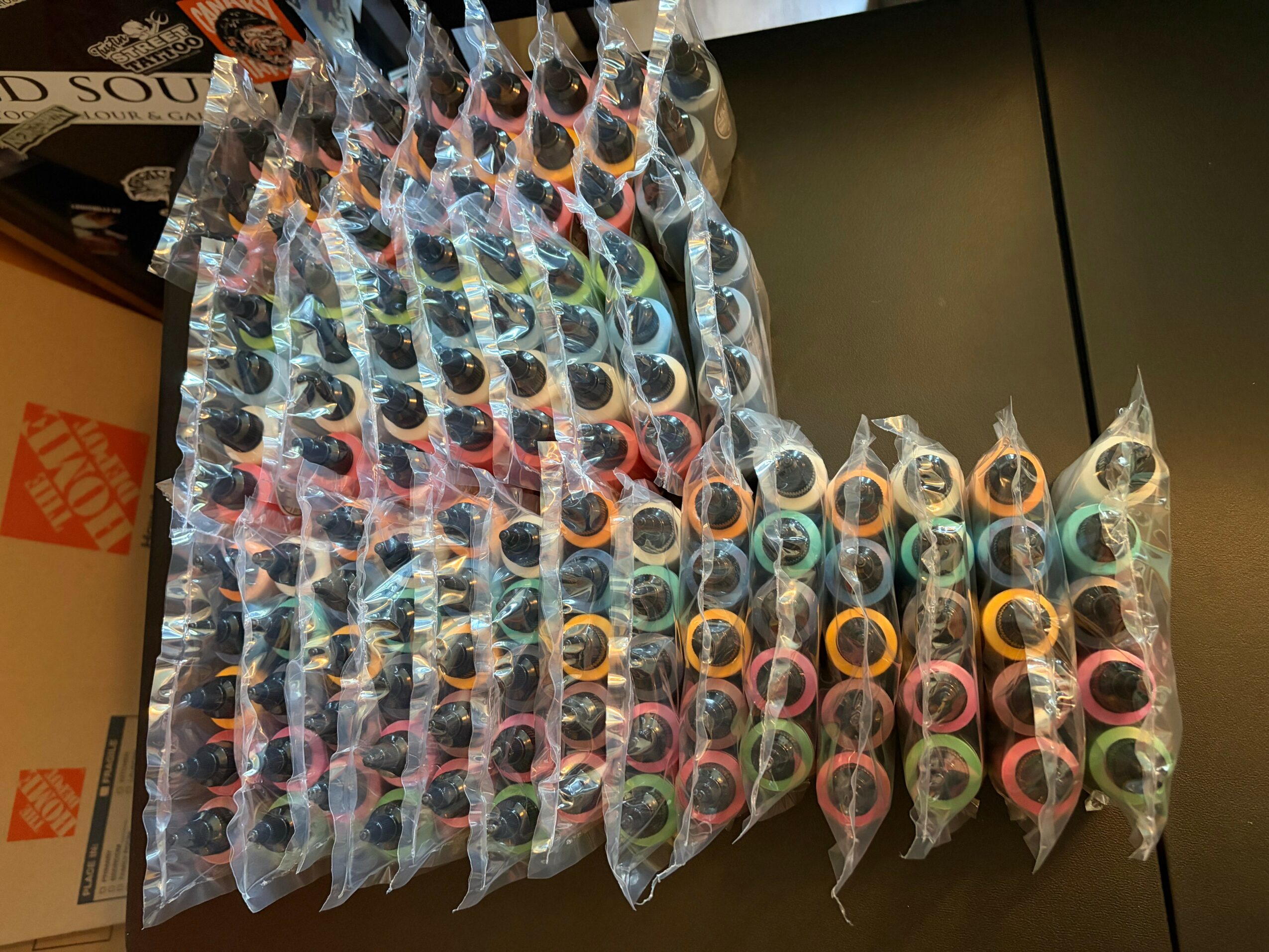 Multiple colorful bottles in clear plastic bags arranged on a black surface.