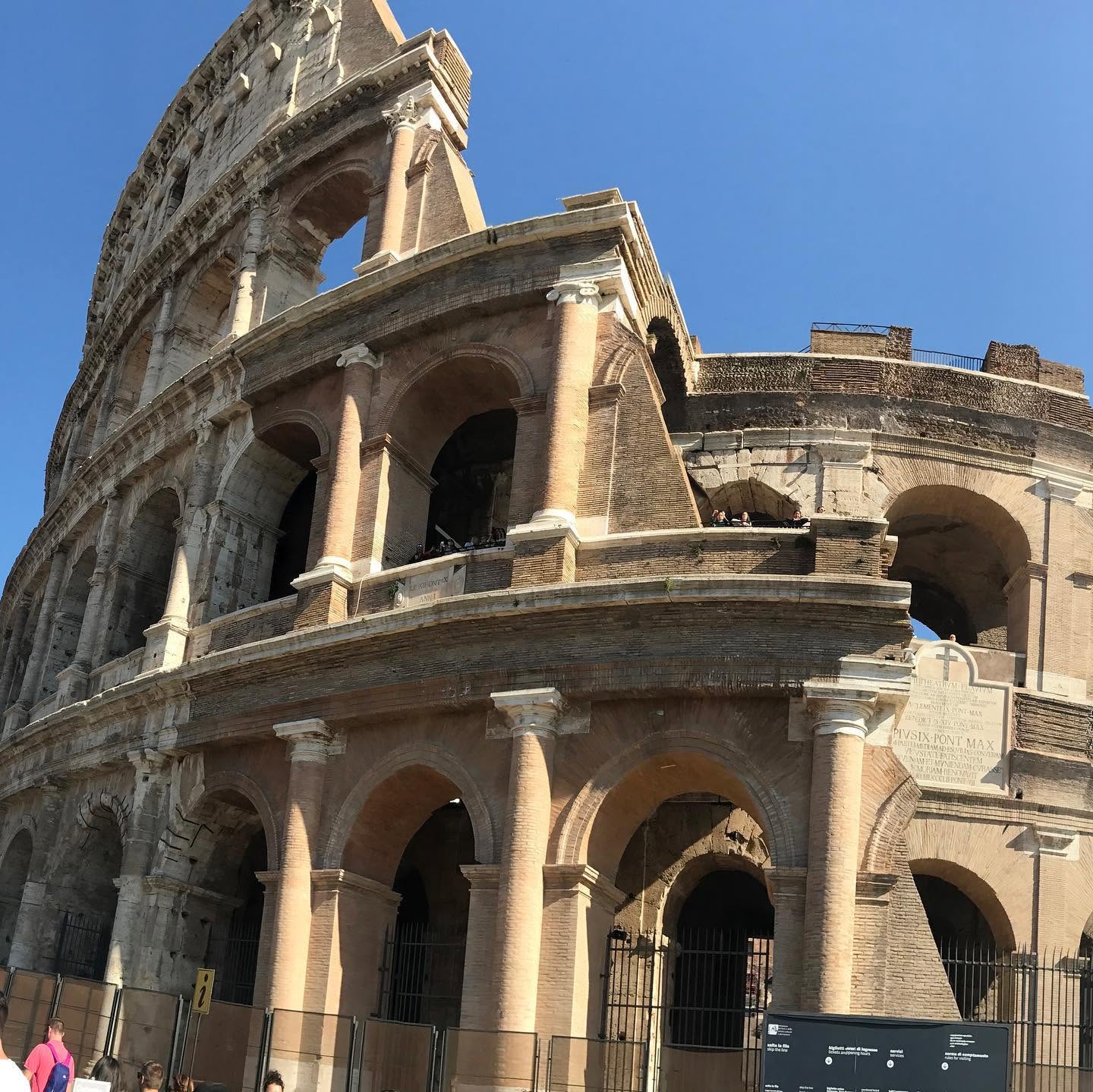 Ancient Roman amphitheater with arches and columns under a clear blue sky.