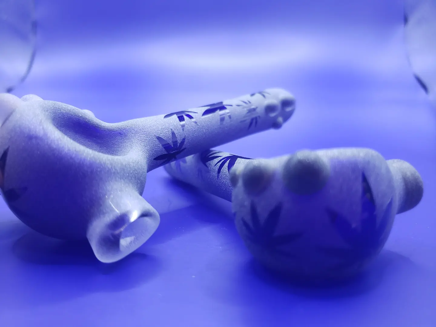 A hand with floral tattoos making a peace sign near a small, rounded object on a blue surface.
