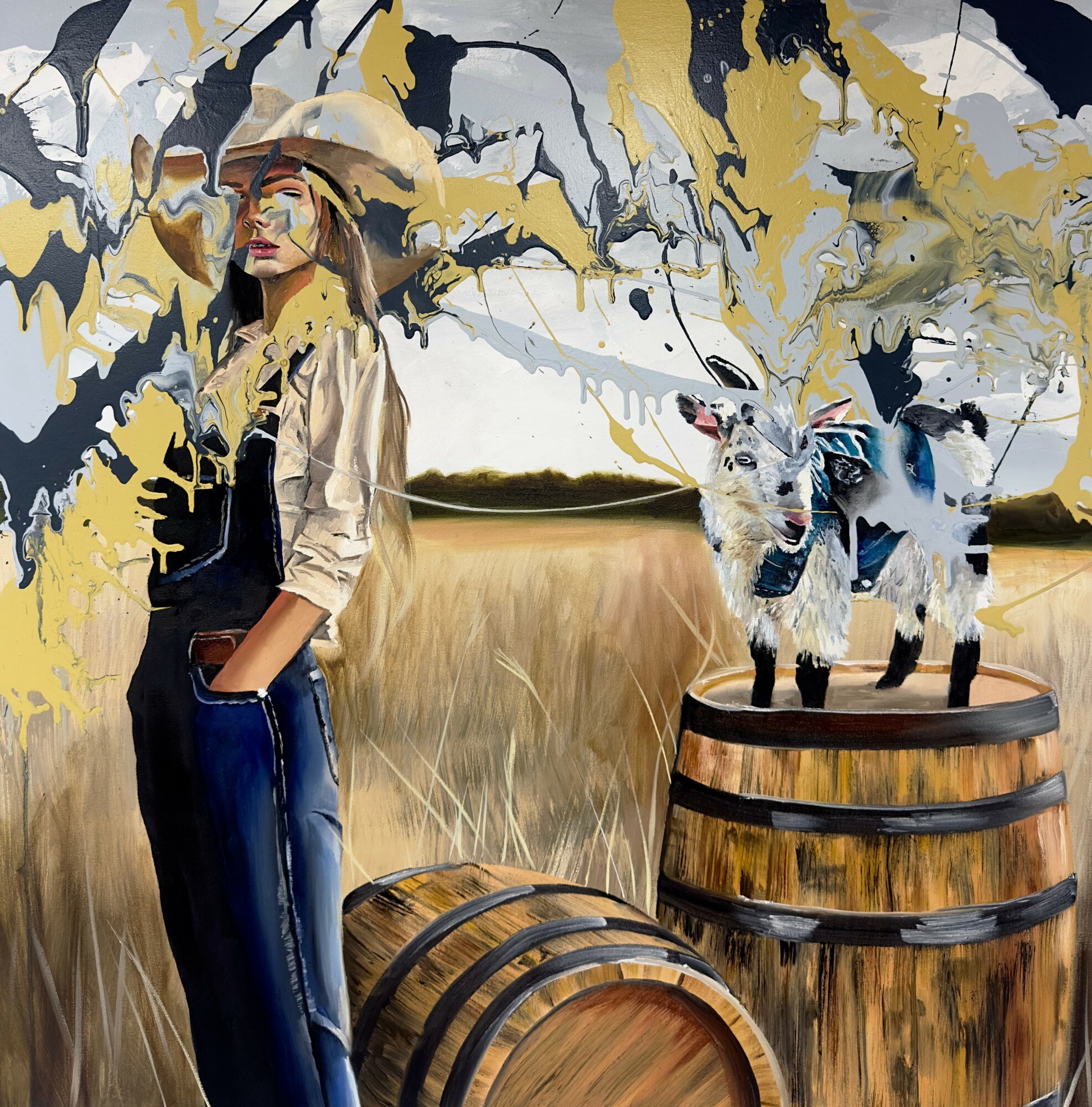 A woman in a hat and sunglasses stands in a field with two goats on a barrel, surrounded by abstract yellow and black paint splashes.