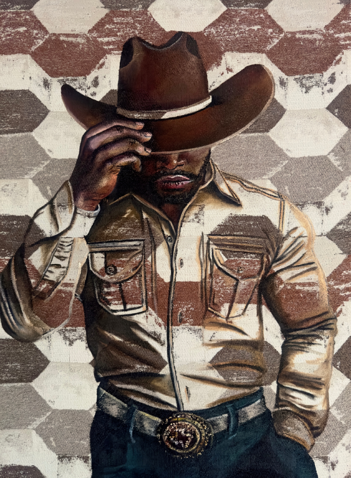 Person wearing a cowboy hat and a beige shirt with chest pockets, standing against a hexagonal patterned background.