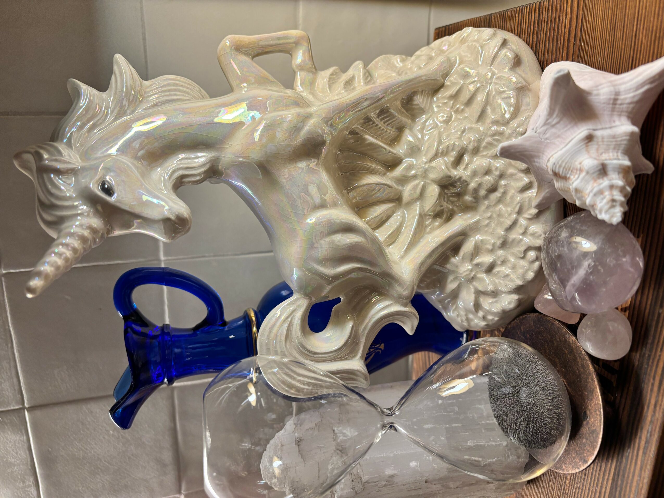 White ceramic dragon sculpture with detailed scales and wings, placed on a surface with decorative objects around it.
