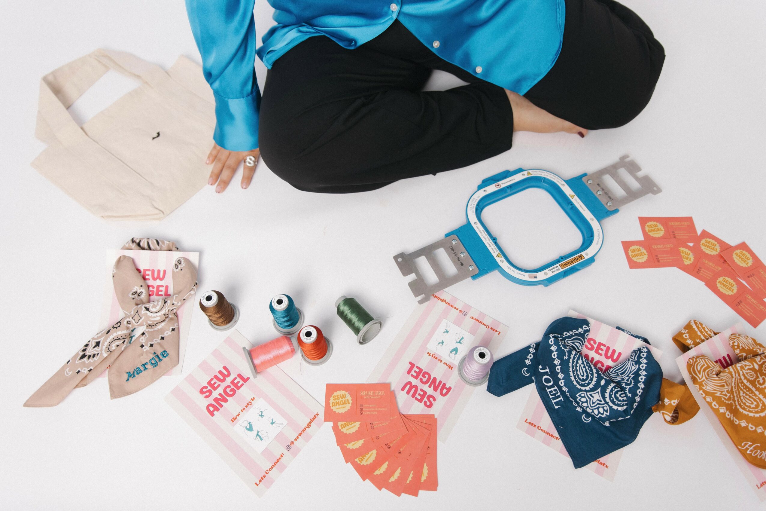 Person sitting cross-legged with gift bags, wrapping paper, and holiday decorations on the floor.