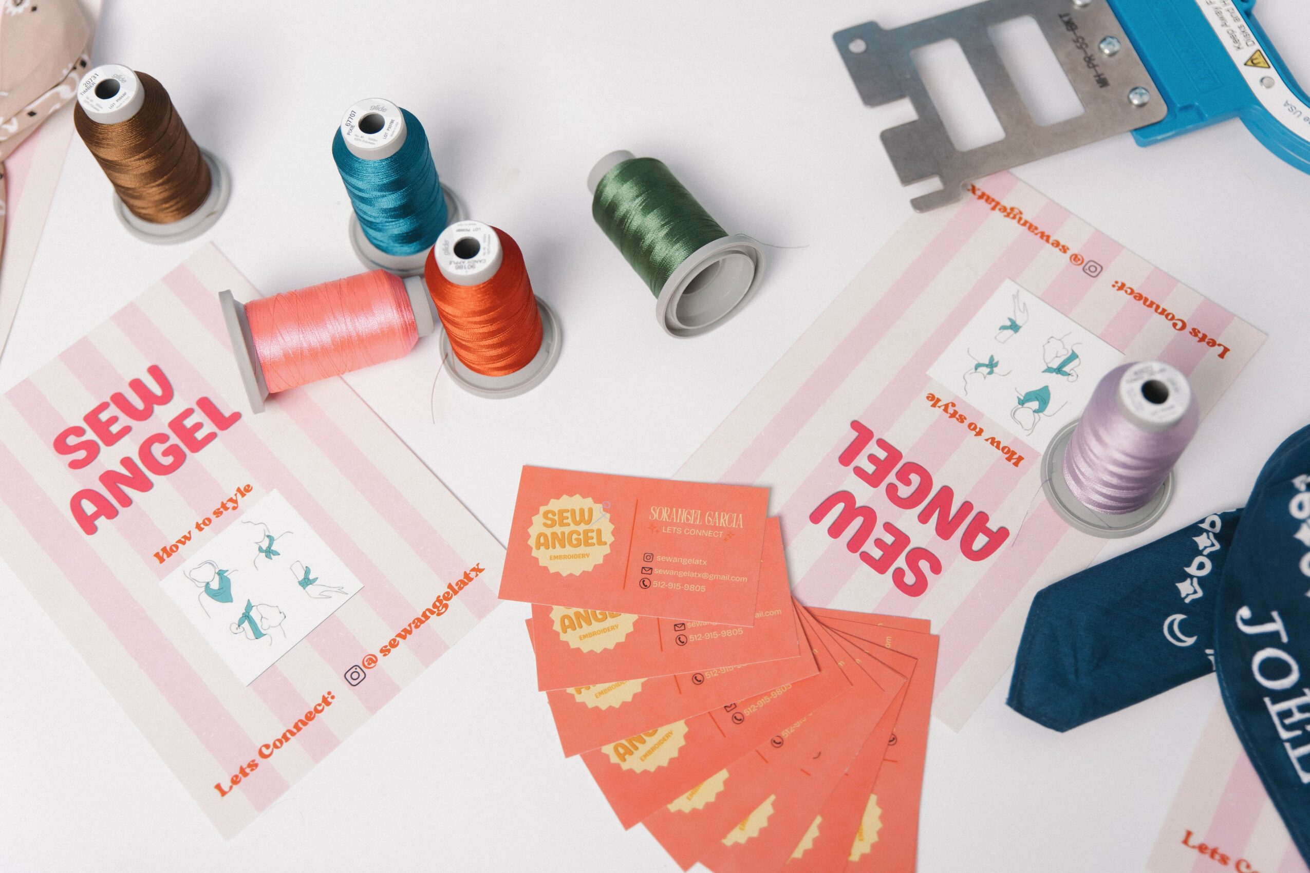 Sewing supplies including spools of thread, sewing patterns, and fabric pieces on a white surface.