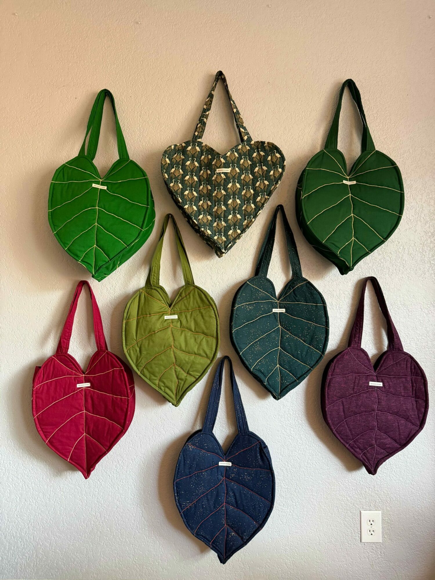 Eight leaf-shaped objects in various colors arranged on a surface, including green, purple, blue, patterned, and red leaves.