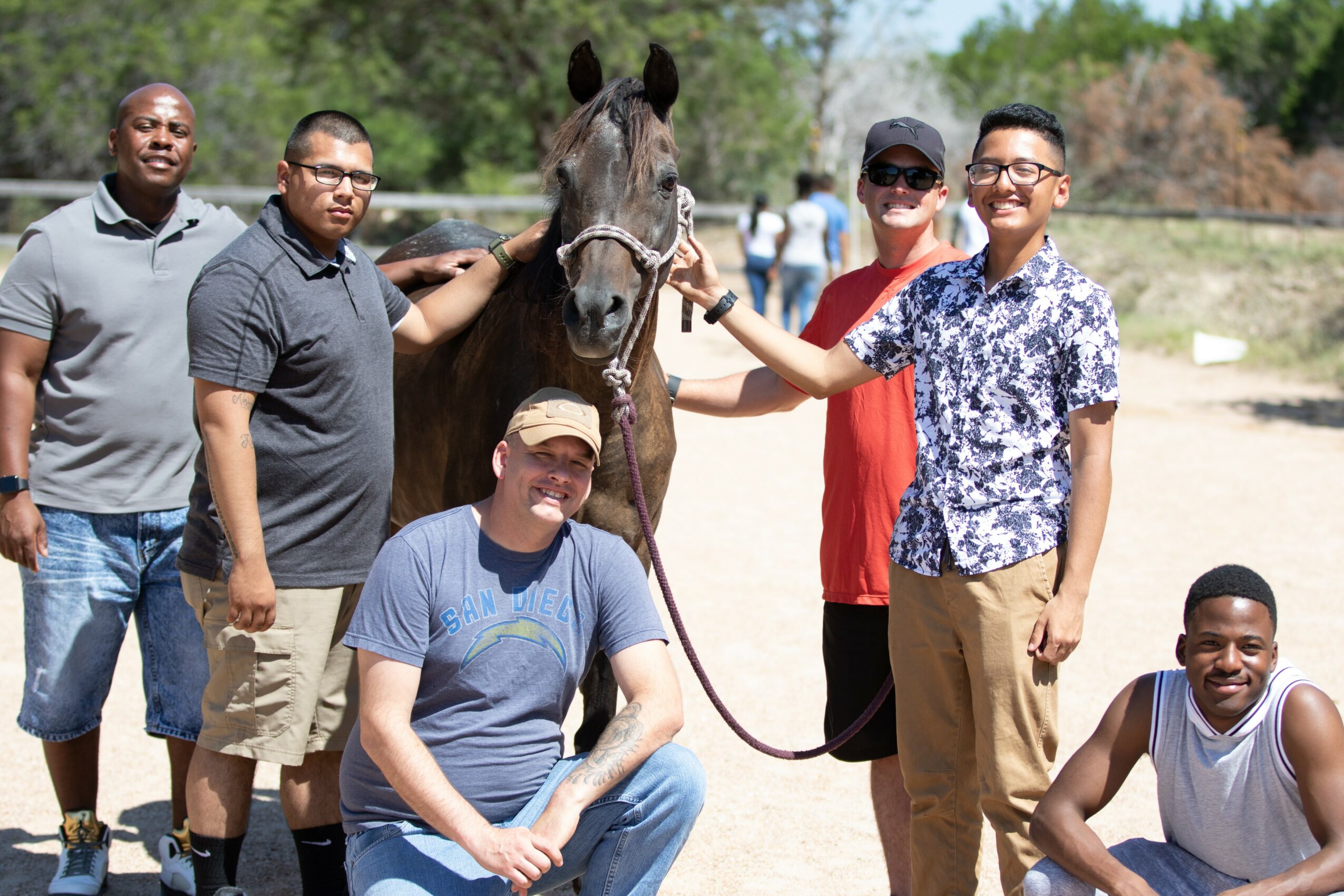 Group of five people and a horse outdoors, smiling and posing for a photo.